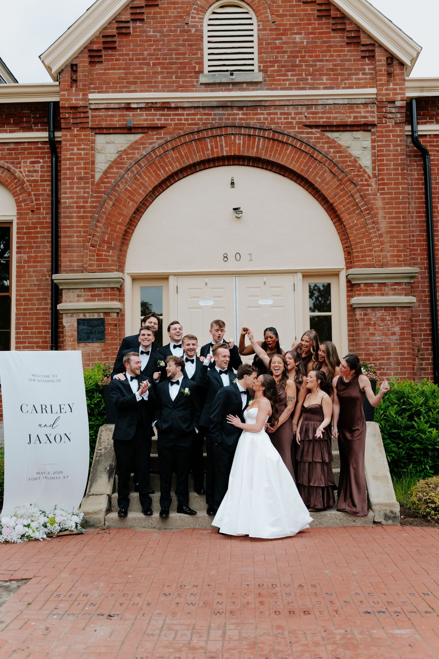 Wedding party celebrates outside brick church with bride and groom Carley and Jaxon, bridesmaids in brown gowns.