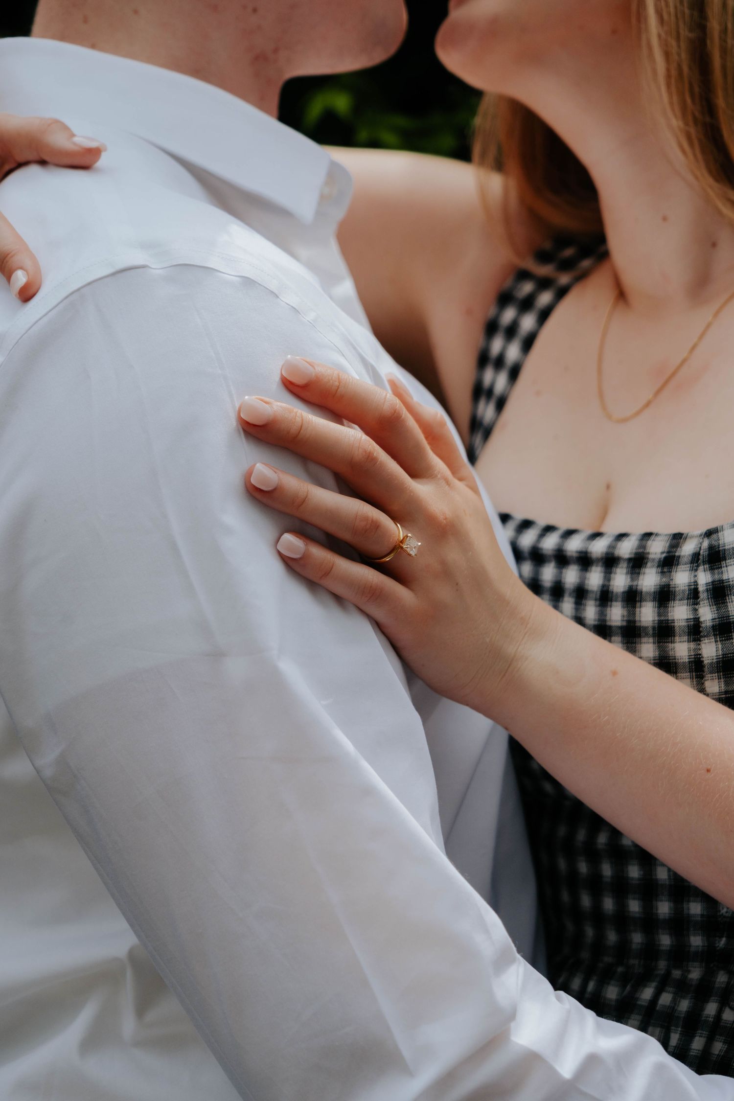 Close up shot of two people embracing while wearing black and white gingham and white formal attire.
