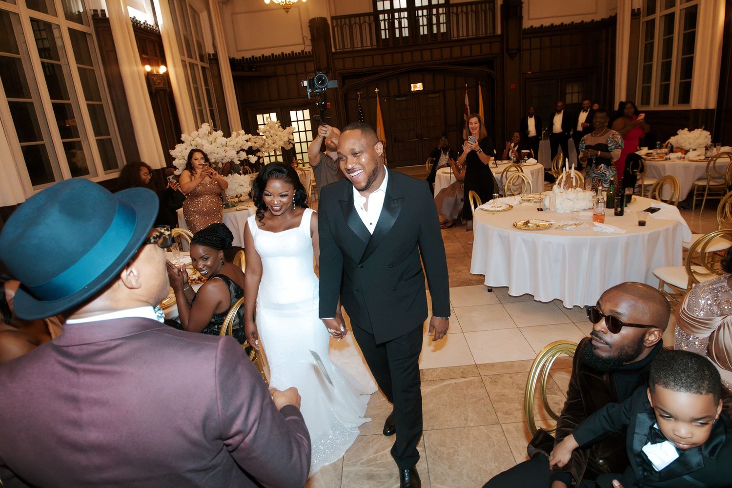 Bride in white gown and groom in black suit make grand entrance at wedding reception.