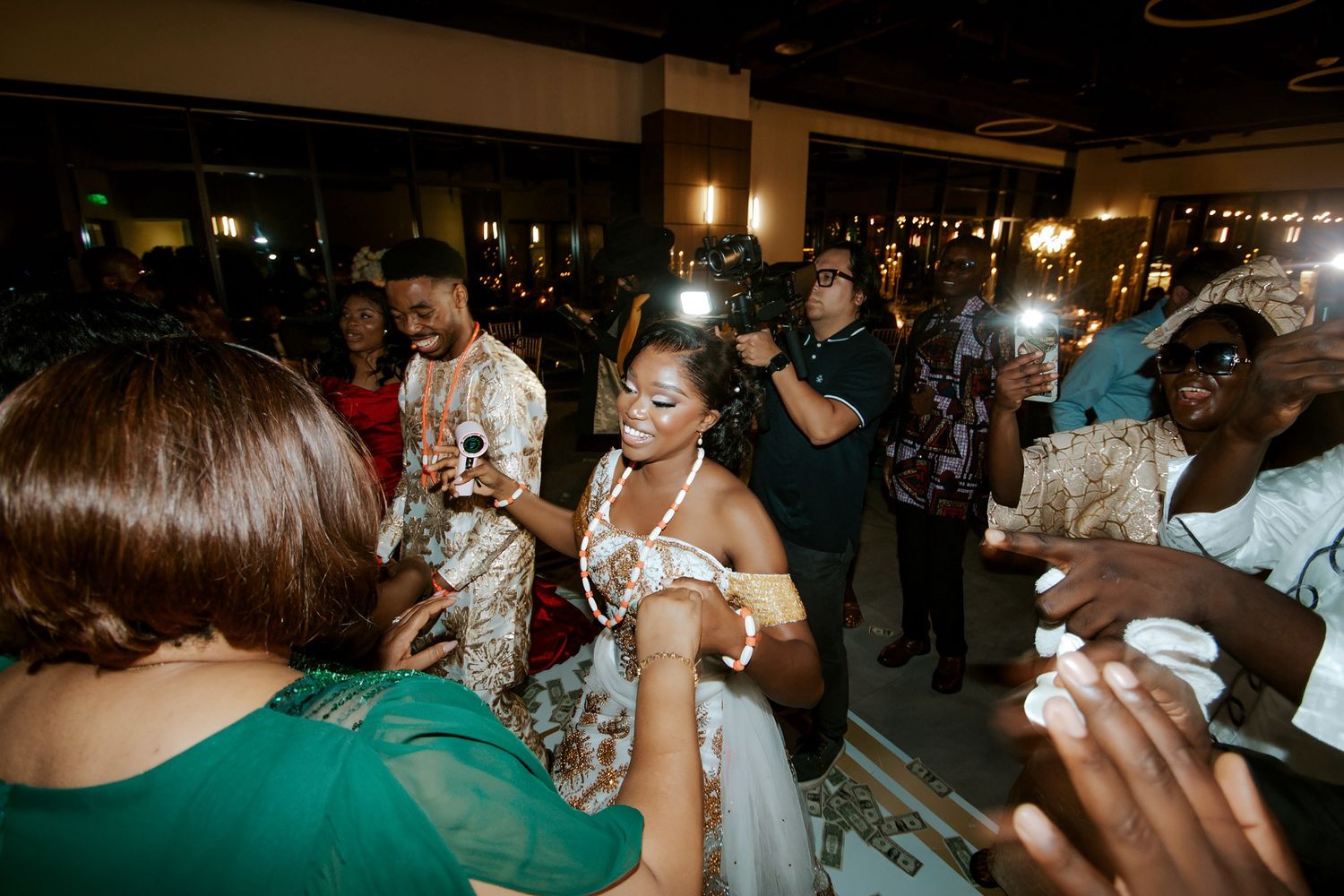 Bride in white gown celebrates with guests during lively indoor wedding reception dance.