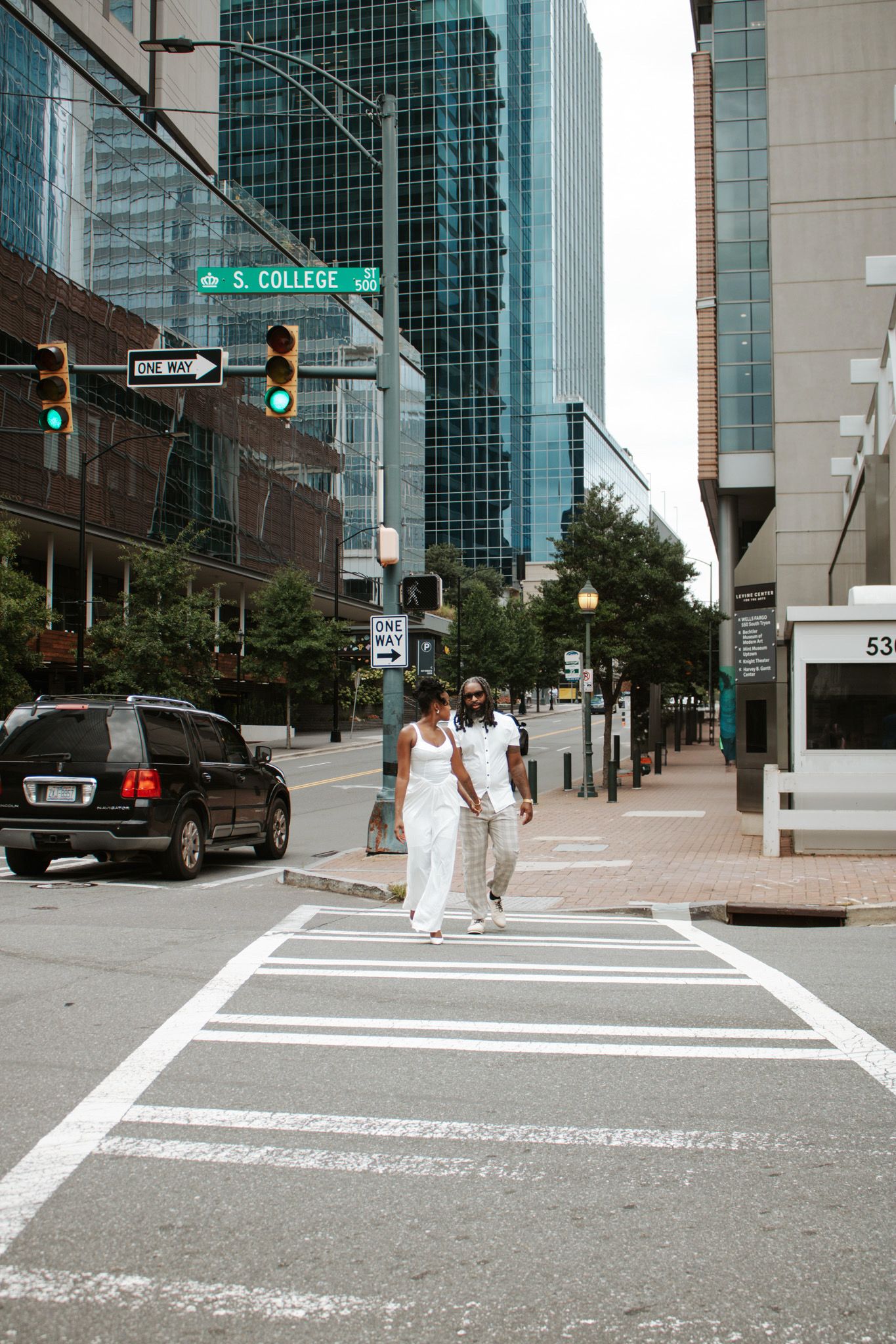 Couple dressed in white crossing a city street at S. College Ave intersection.
