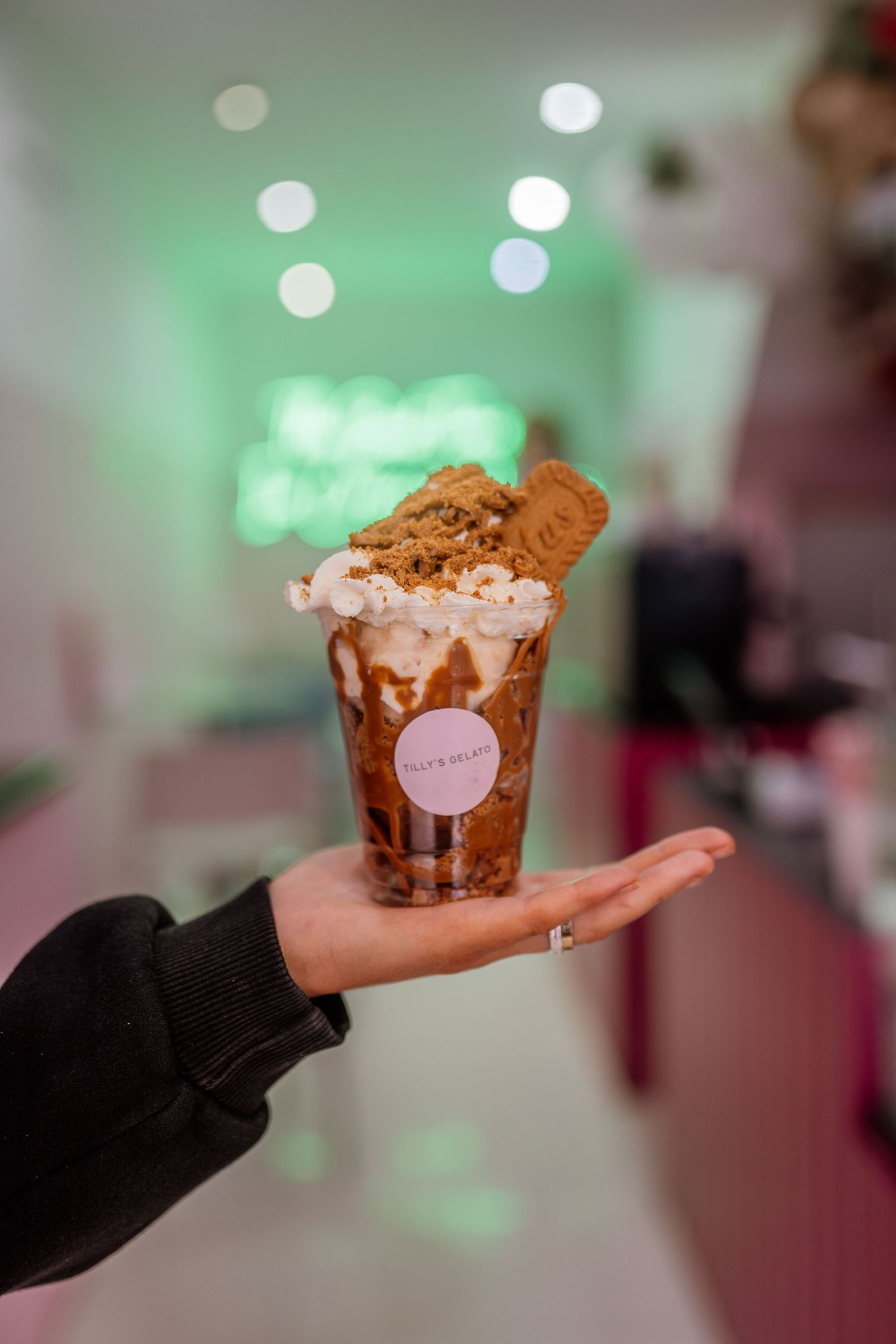 Dessert cup with whipped cream and cookie garnish presented against green ambient lighting.