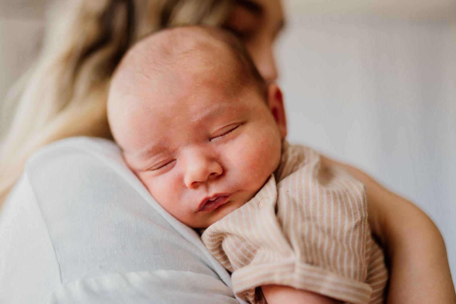 Tender newborn photography session featuring soft beige tones and gentle natural lighting.
