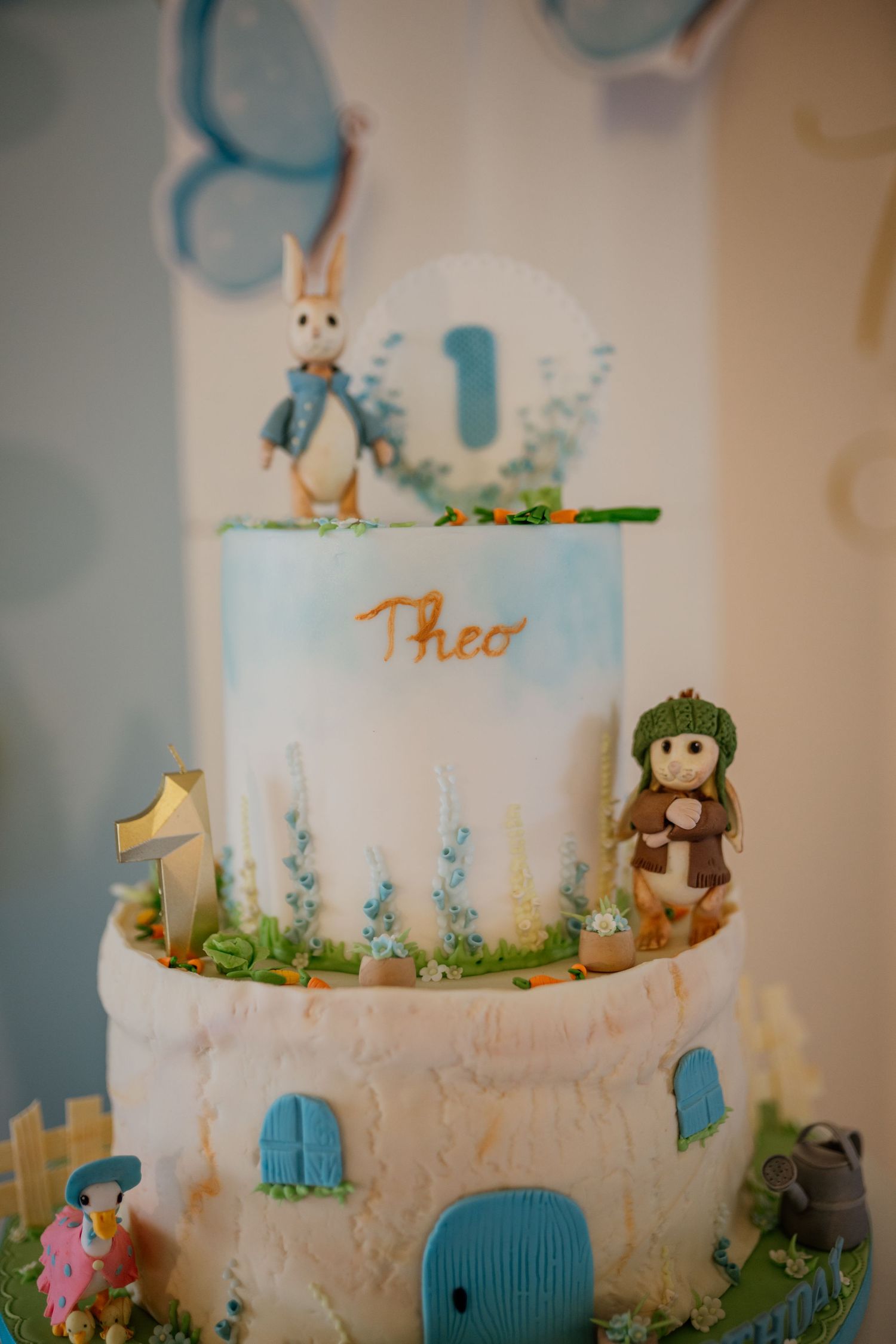 A whimsical tiered cake decorated with blue accents and garden-themed details.