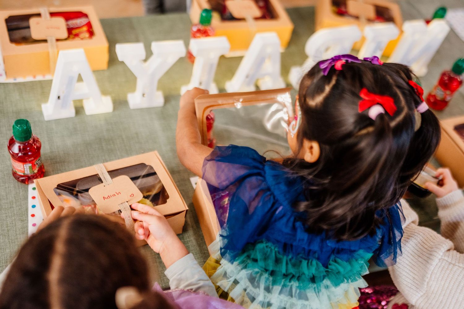 Children in colorful tutus participate in a dance activity at an indoor party.
