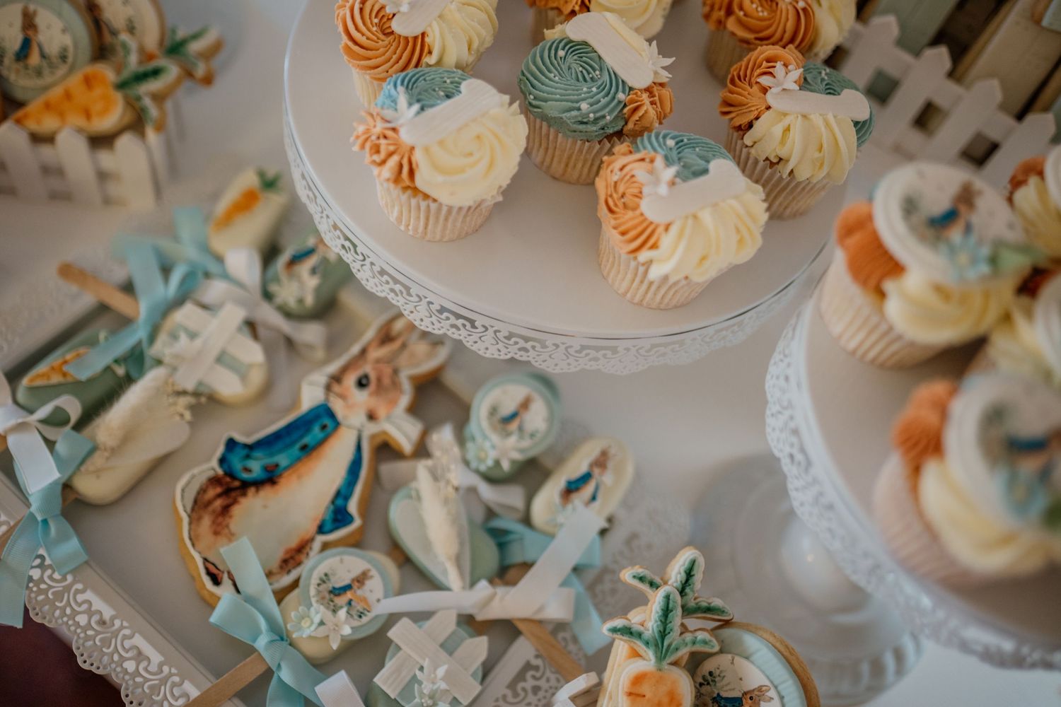 Display of elegant cupcakes decorated in turquoise and cream colors on tiered stands.