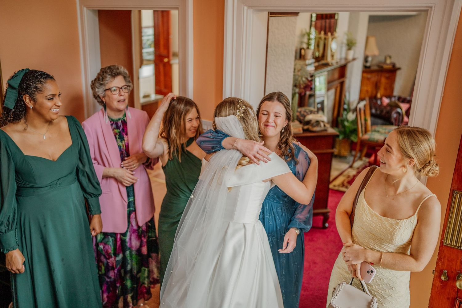 A group of people dancing and celebrating together at a wedding reception in a bright indoor venue.