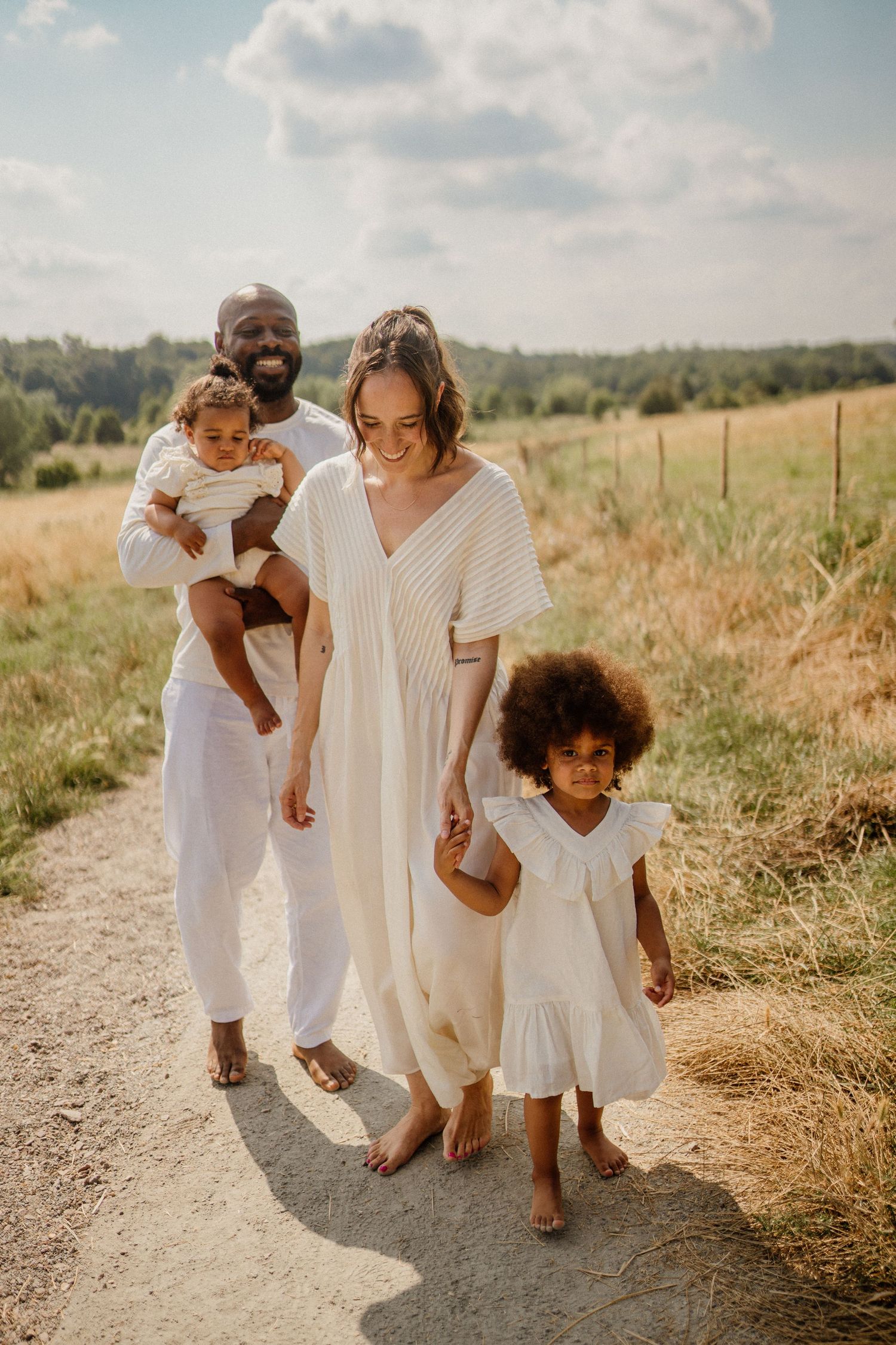 Family walking together on rural path wearing coordinated white outfits.