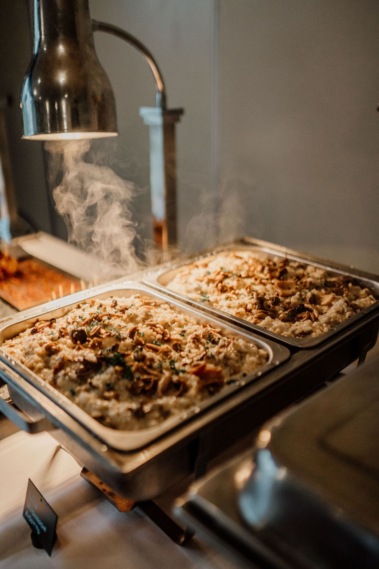 Steaming hot food on a large serving tray at a catering event.