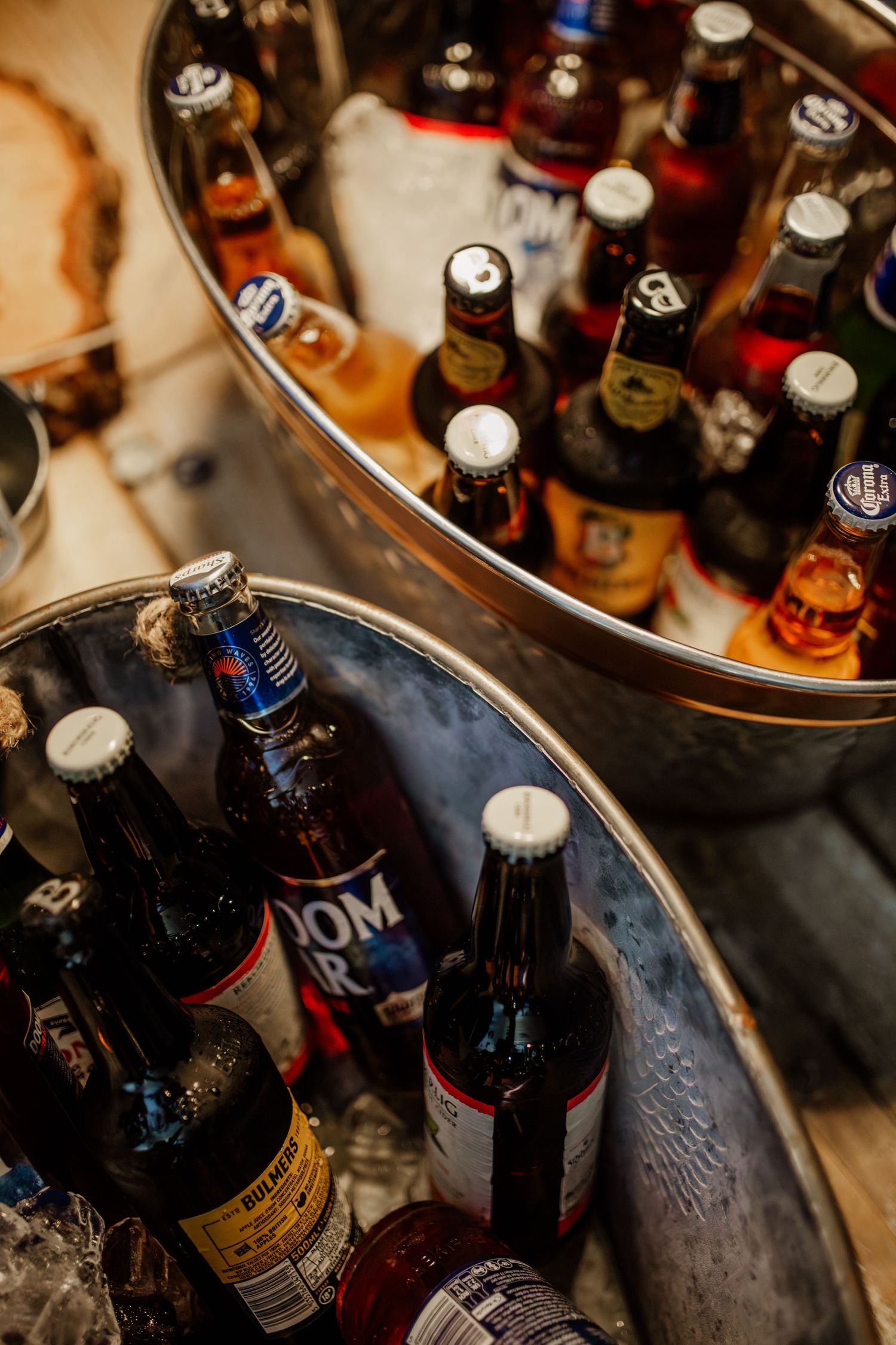 Assorted beer bottles chilling in metal ice buckets at a wedding reception.