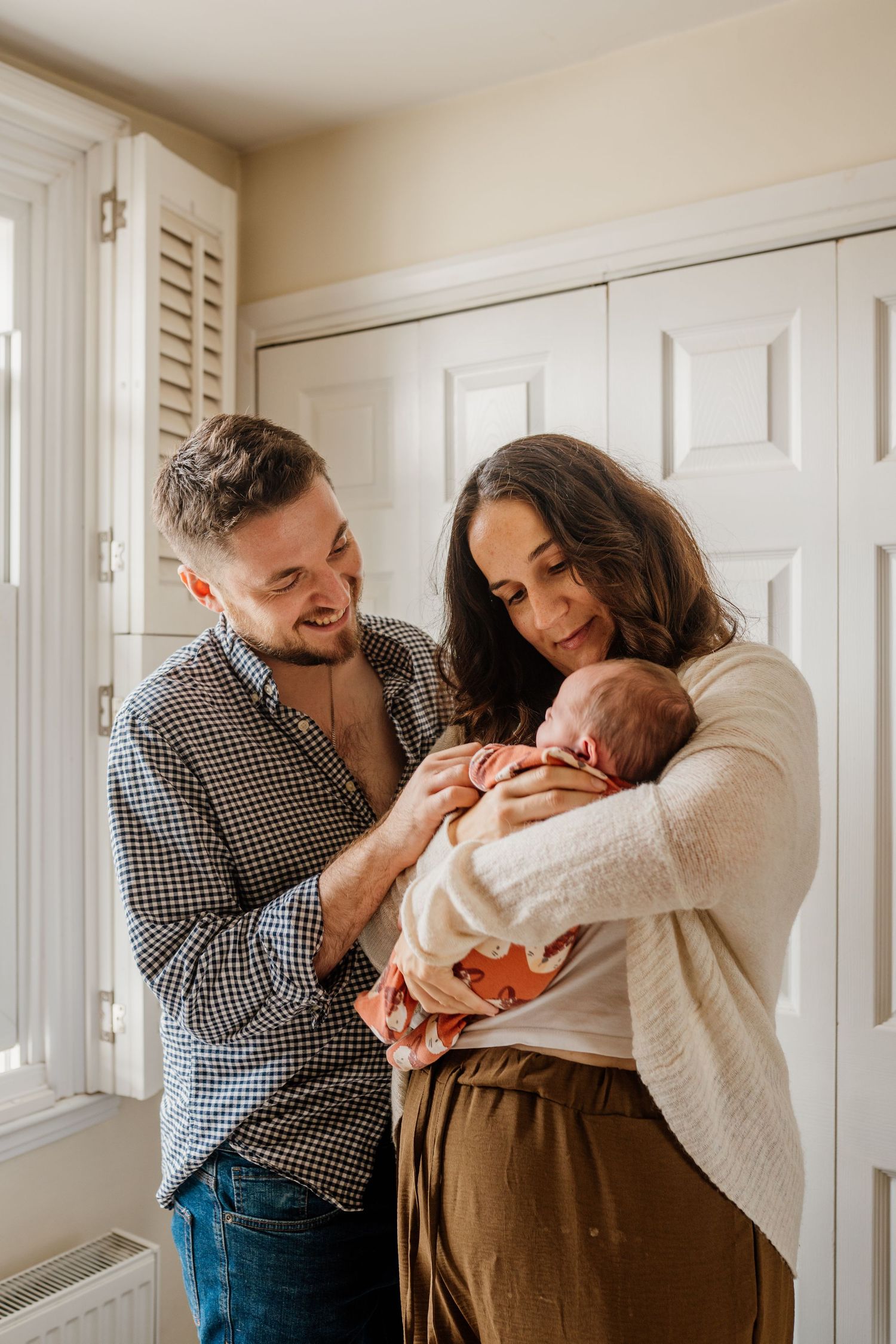 Family sharing joyful moment with newborn baby in bright interior room.