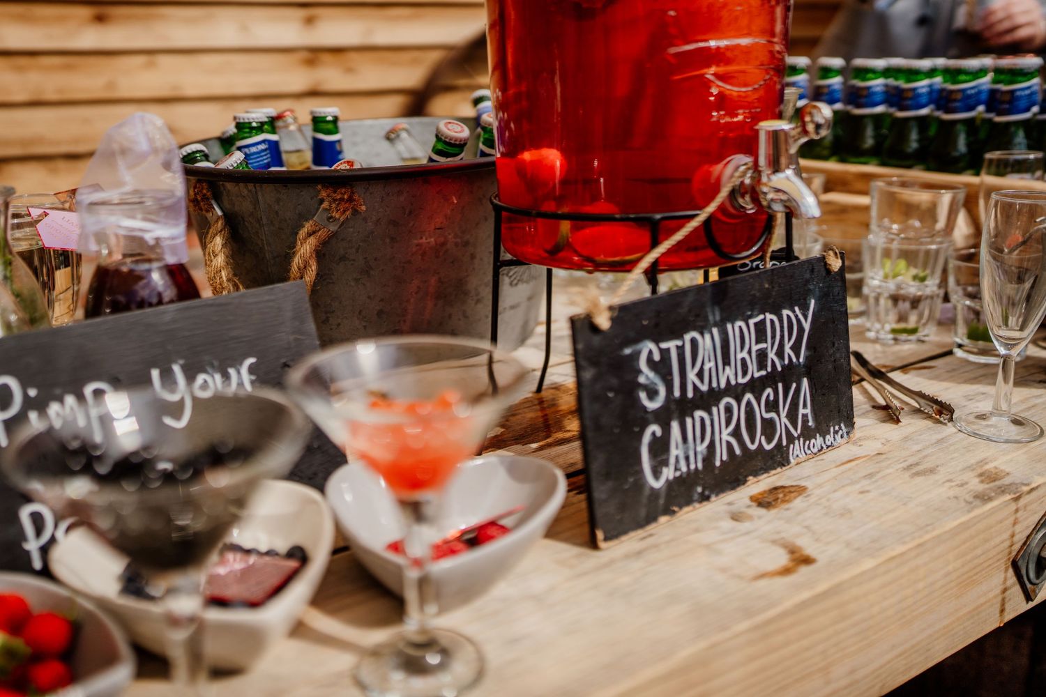Rustic drink station with chalkboard signs and beverage dispensers at wedding reception.