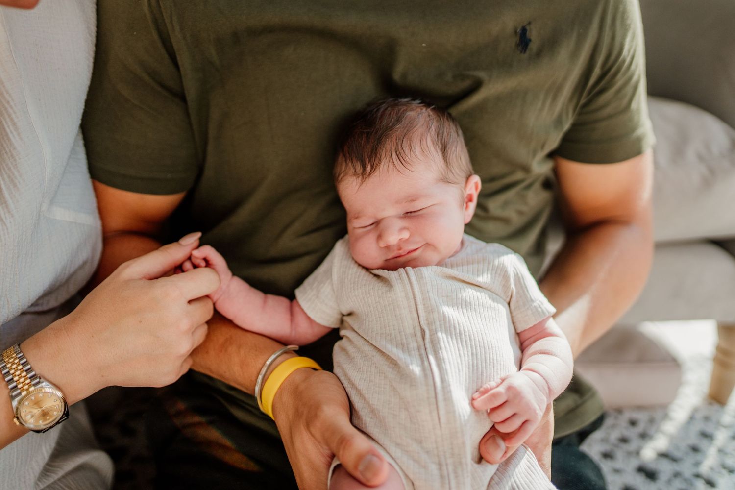Tender moments of parents holding their newborn baby in a cozy indoor setting.