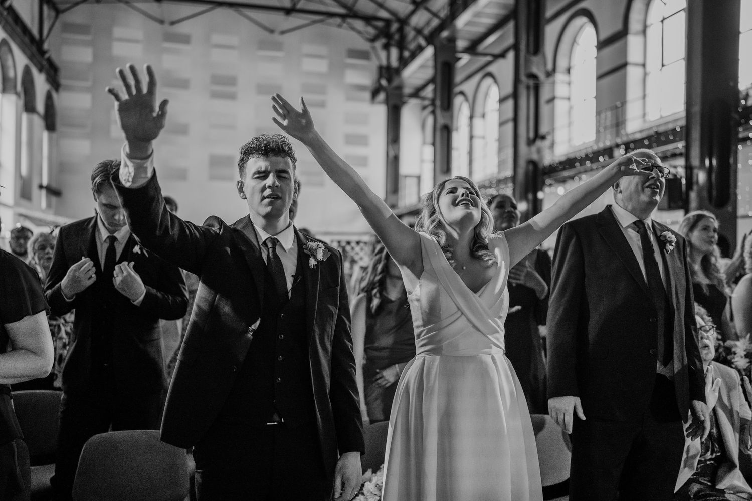 Black and white photo of wedding guests celebrating during a reception.