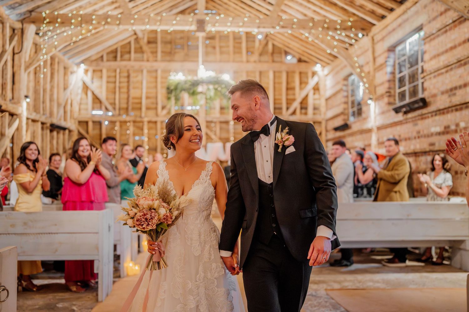 Wedding guests dance and celebrate together in a rustic wooden barn venue during a joyful reception.