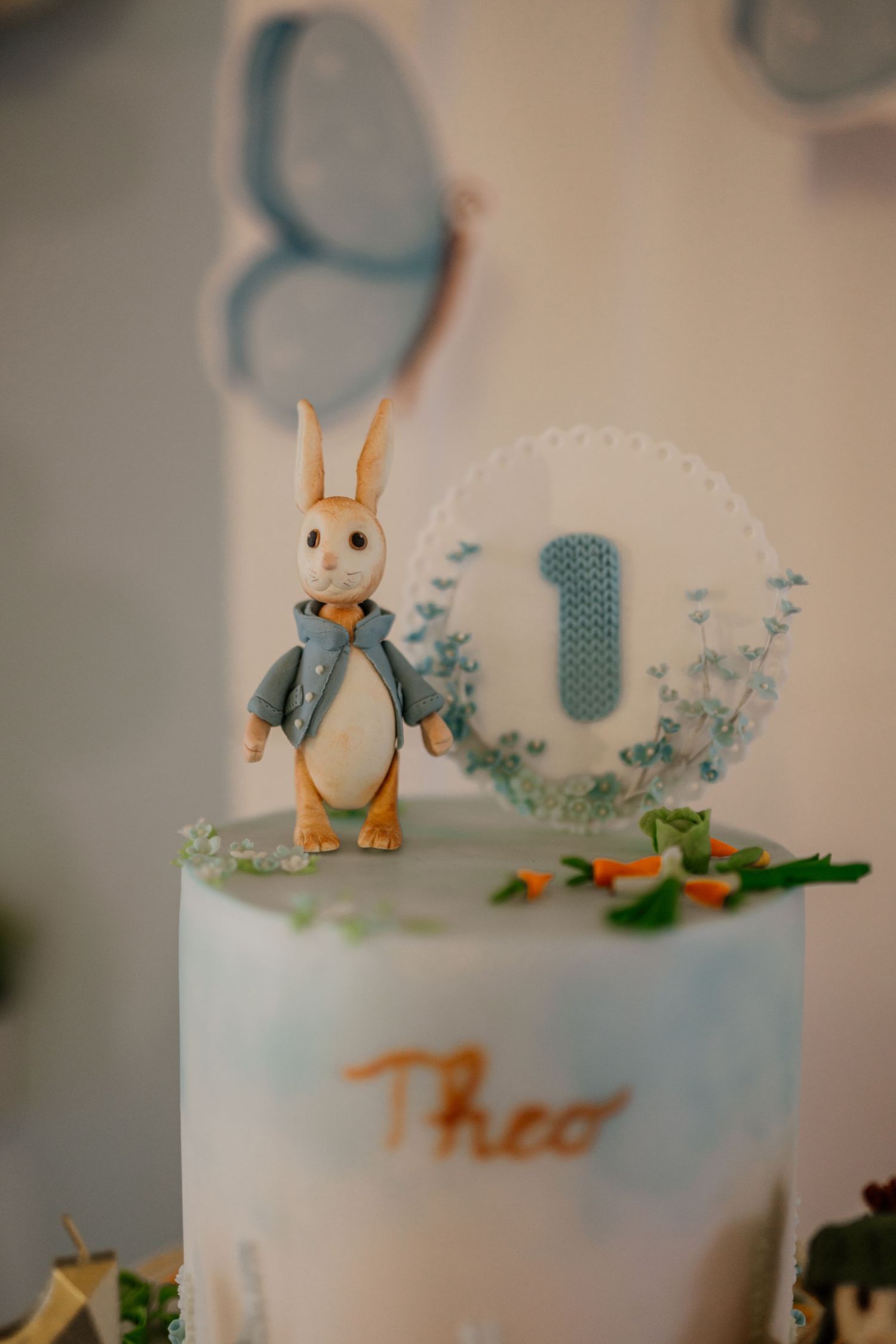 Decorative cake topper featuring blue elephants and bunnies in a whimsical garden scene.