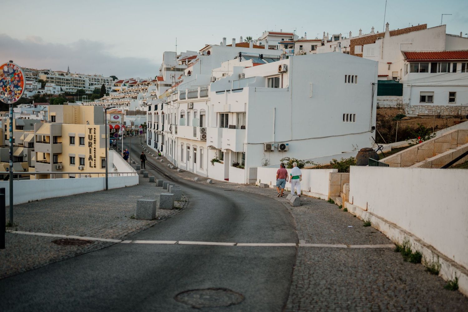Panoramic view of white buildings along hillside streets in a coastal town.