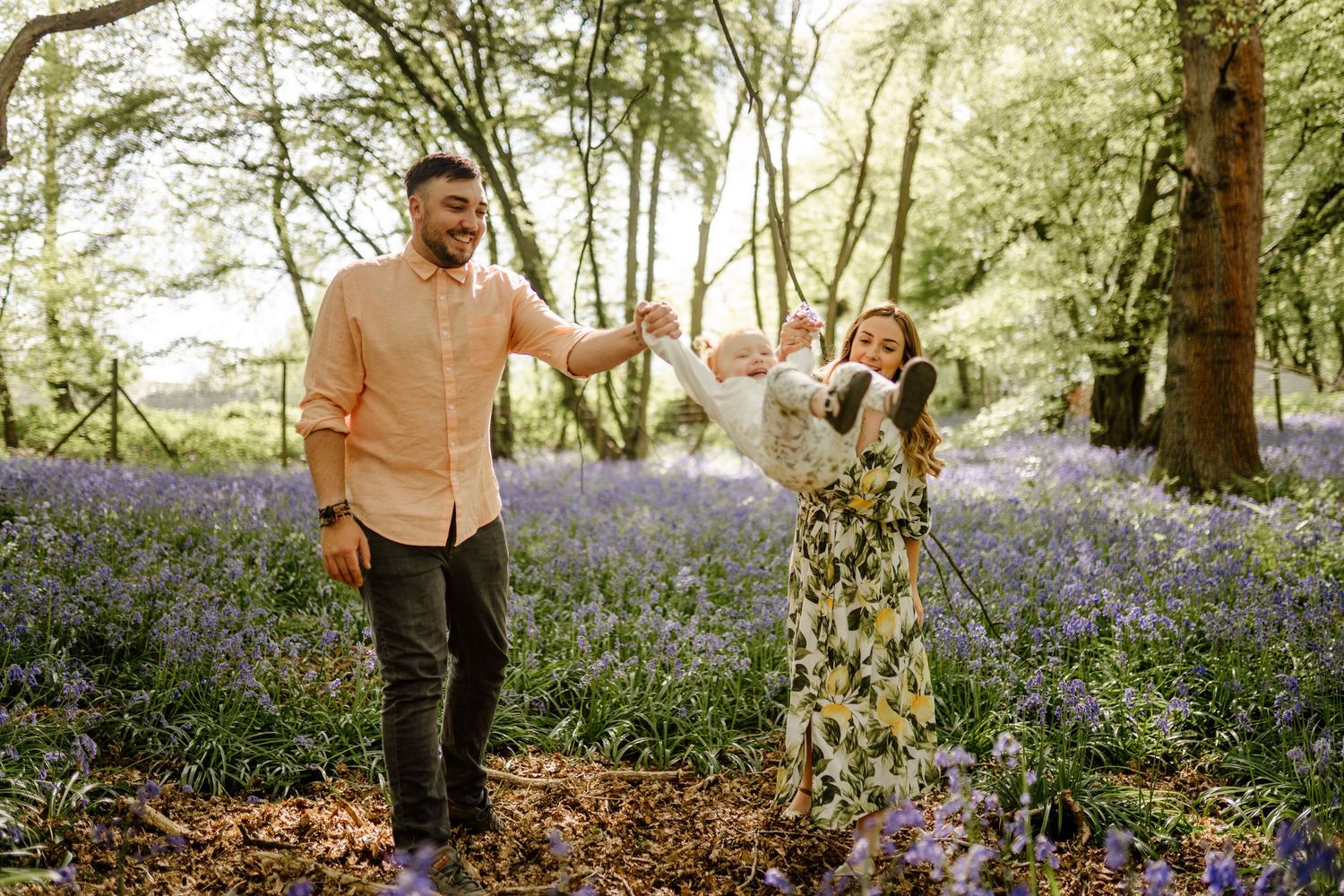 A couple walks through a beautiful spring forest filled with blooming purple bluebells in Hertfordshire creating a magical atmosphere.