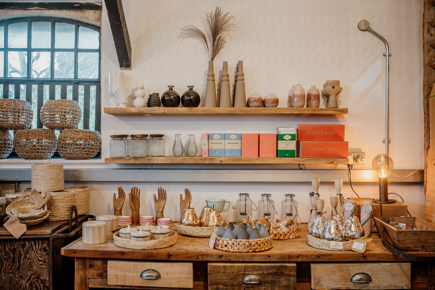 Rustic wooden shelves displaying handmade pottery, glassware, and decorative items in a cozy retail shop interior.