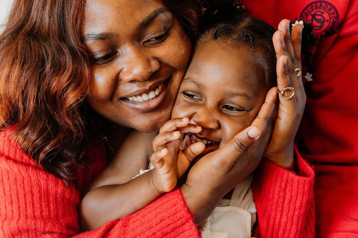 Joyful family moments captured against a vibrant red background in close-up shots.