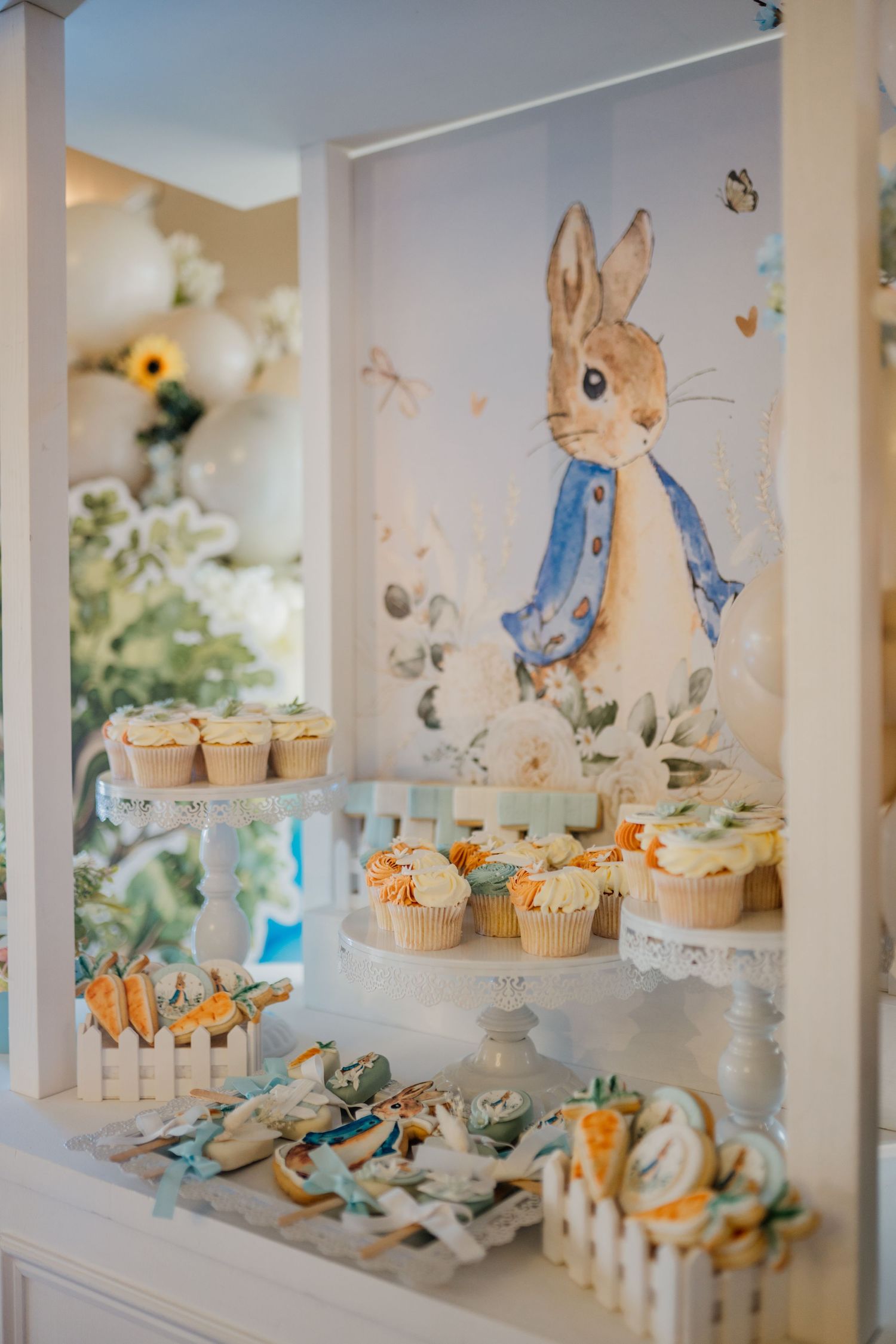 Peter Rabbit themed dessert display with cupcakes and decorative elements in soft blue and white.