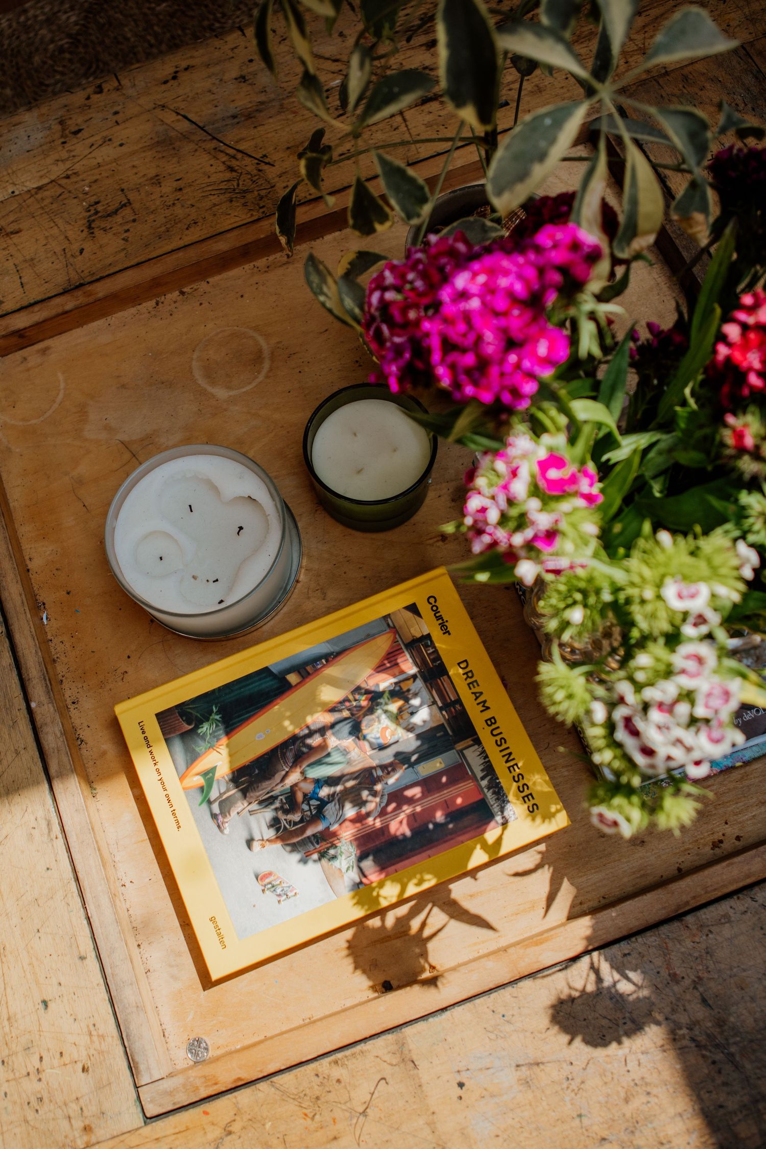 Rustic wooden table with photographs and vibrant pink flowers in decorative arrangements.