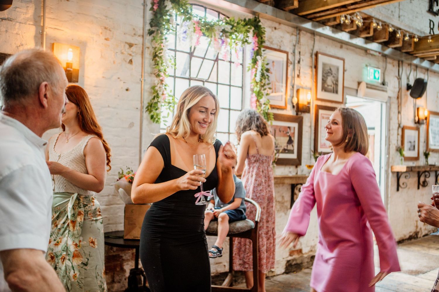 Industrial style venue with exposed brick walls and hanging plants during a social gathering.