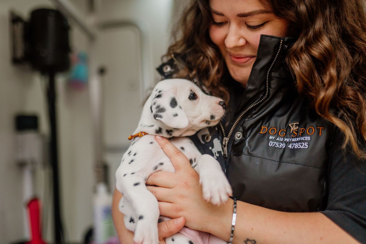 Small white puppy being held and cuddled by someone wearing black.