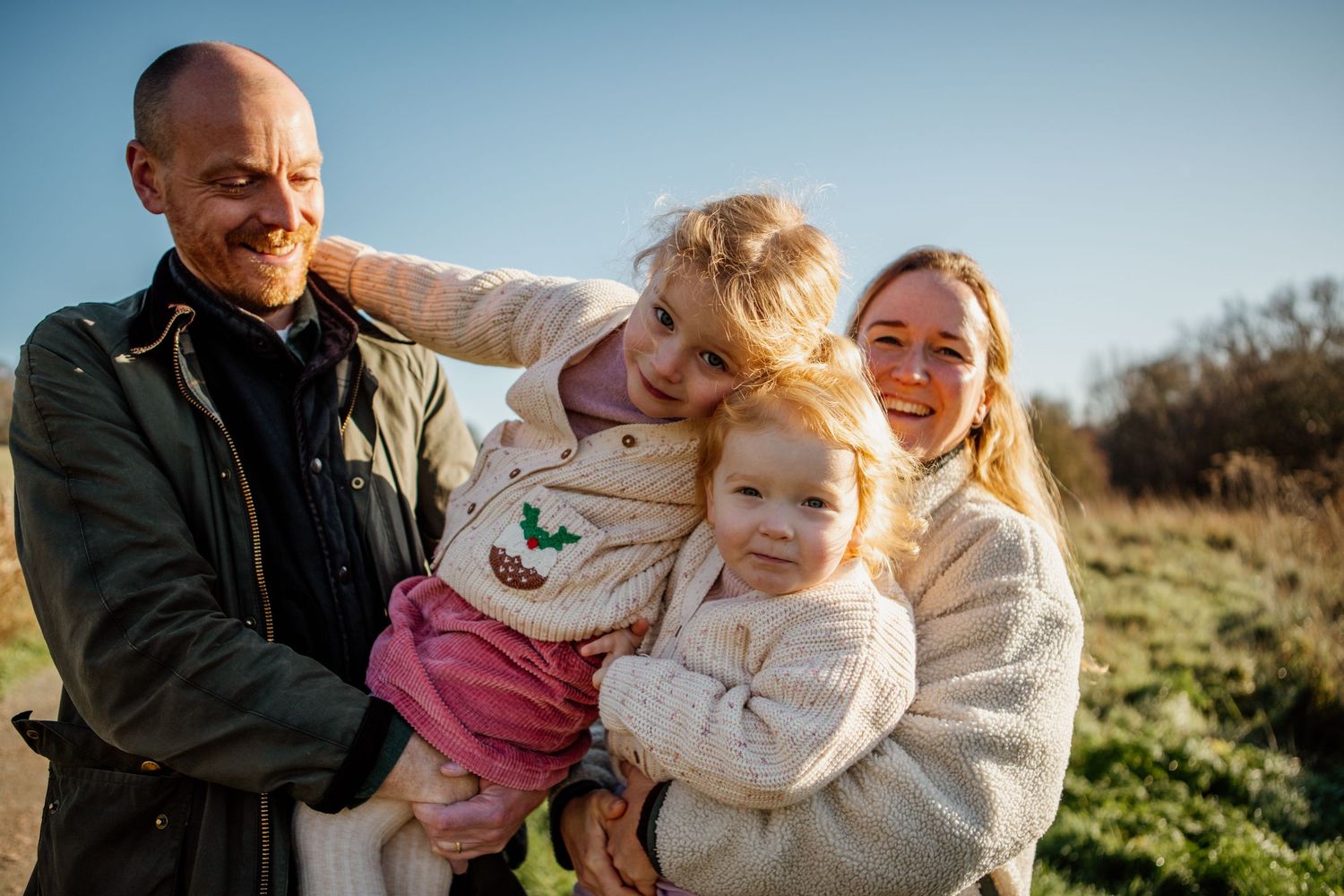 A family shares a playful outdoor moment together on a sunny day in a field.
