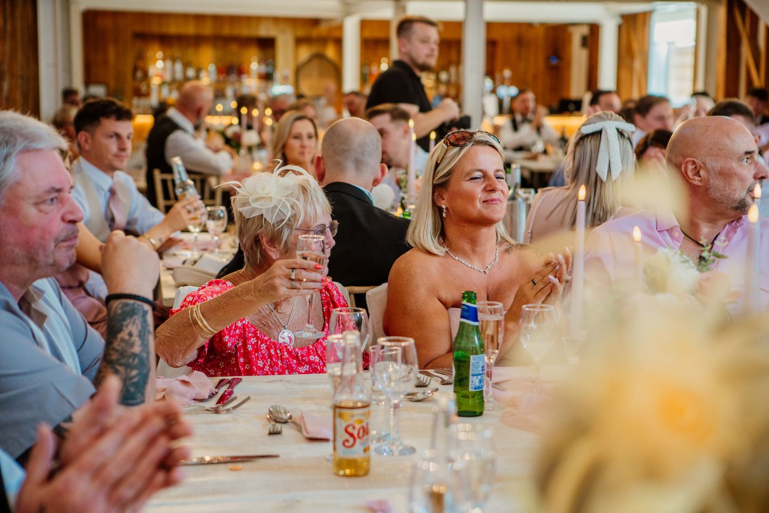Wedding reception guests seated at long tables enjoying dinner and conversation.