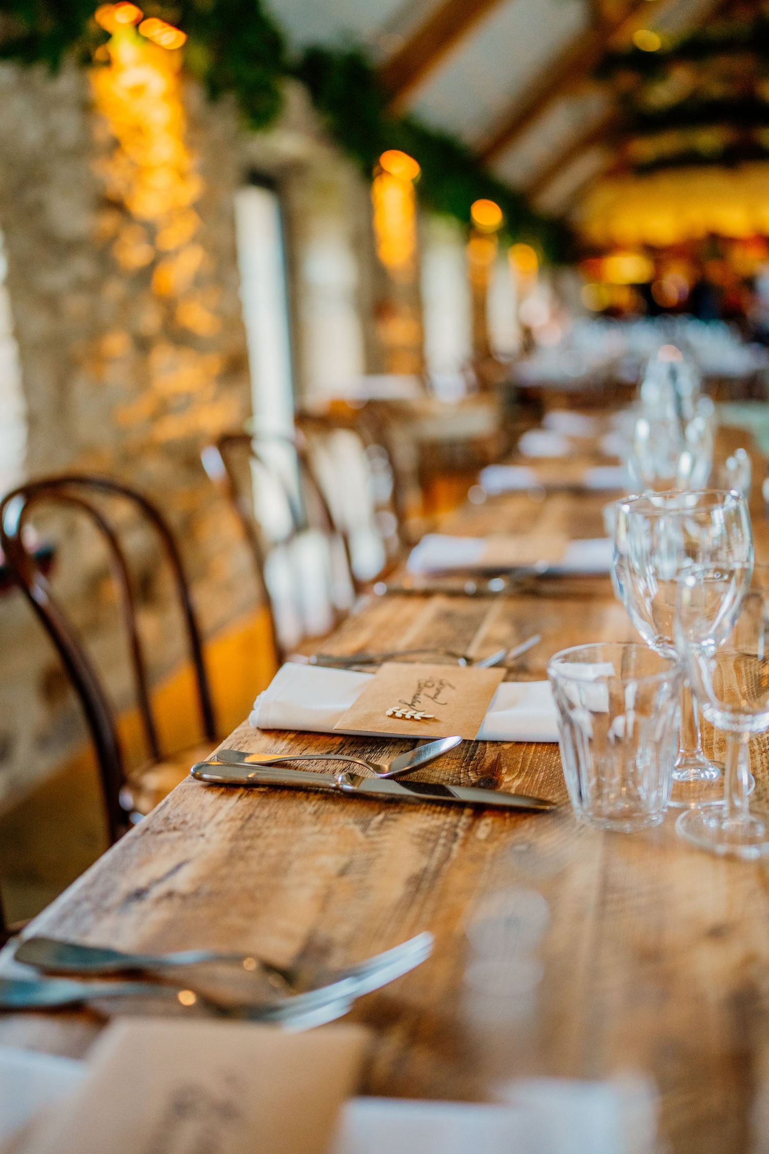 Close-up of rustic wedding reception table settings with glassware and wooden details.