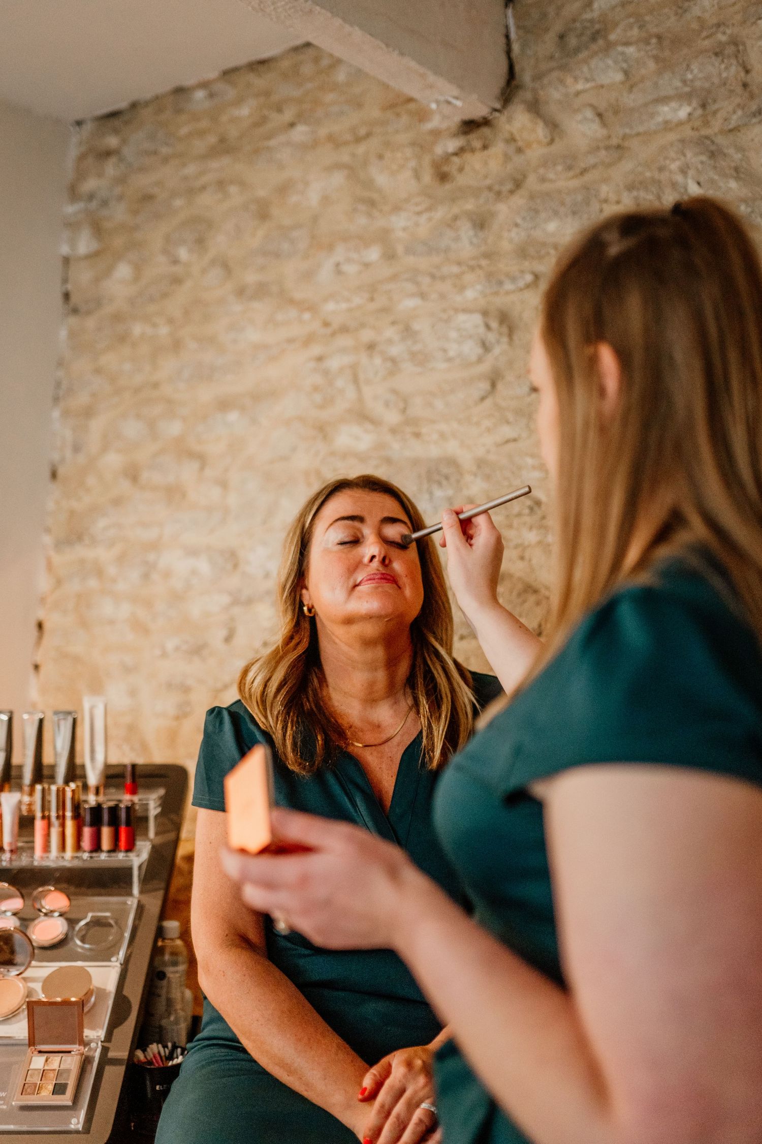 Beauty service being performed in a rustic setting with exposed brick walls.