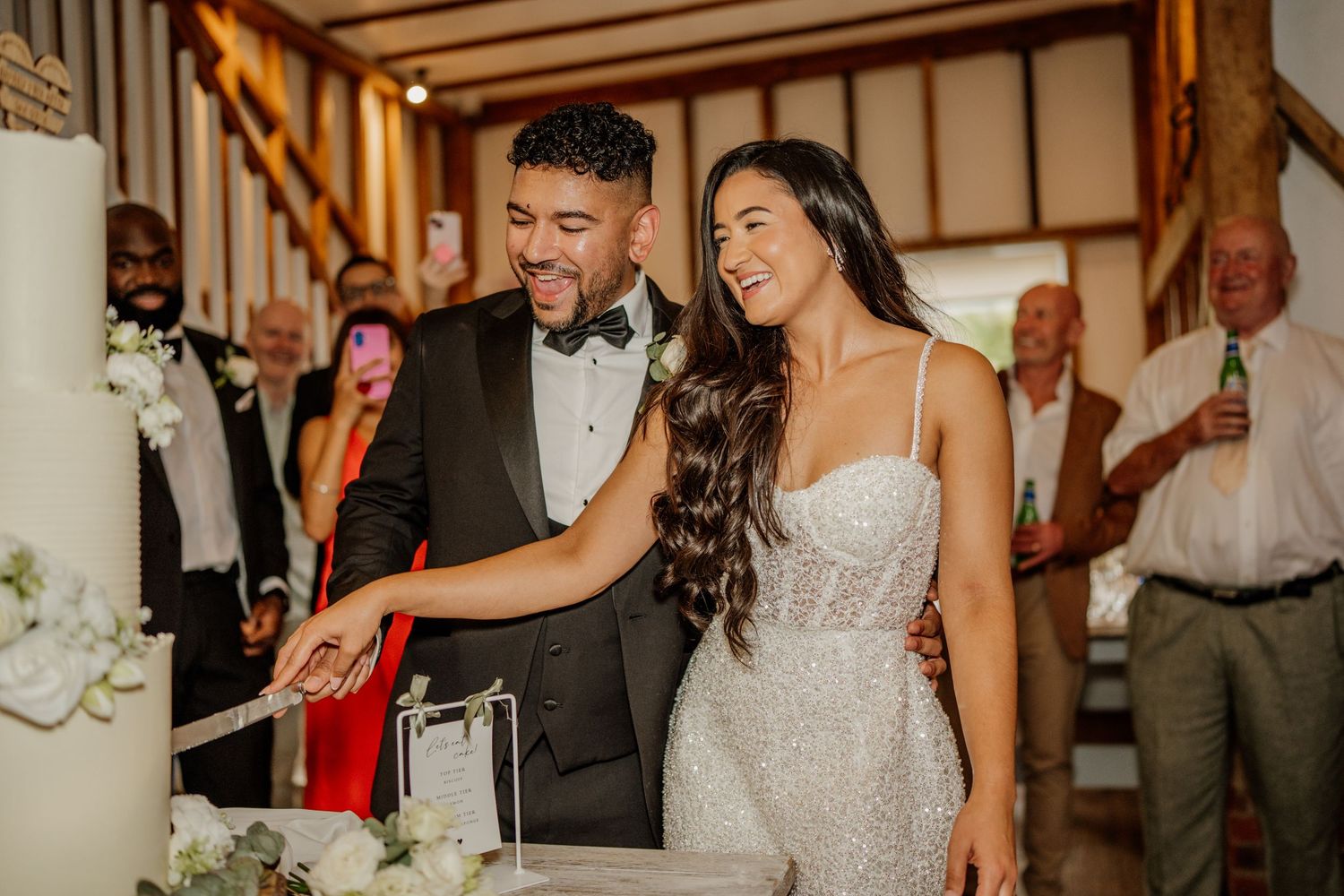 Wedding reception guests raise champagne glasses in celebration during an indoor venue toast.