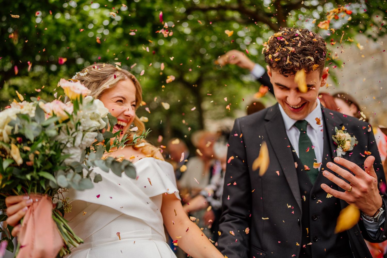 Confetti shower moment during wedding celebration in a sunlit garden setting.