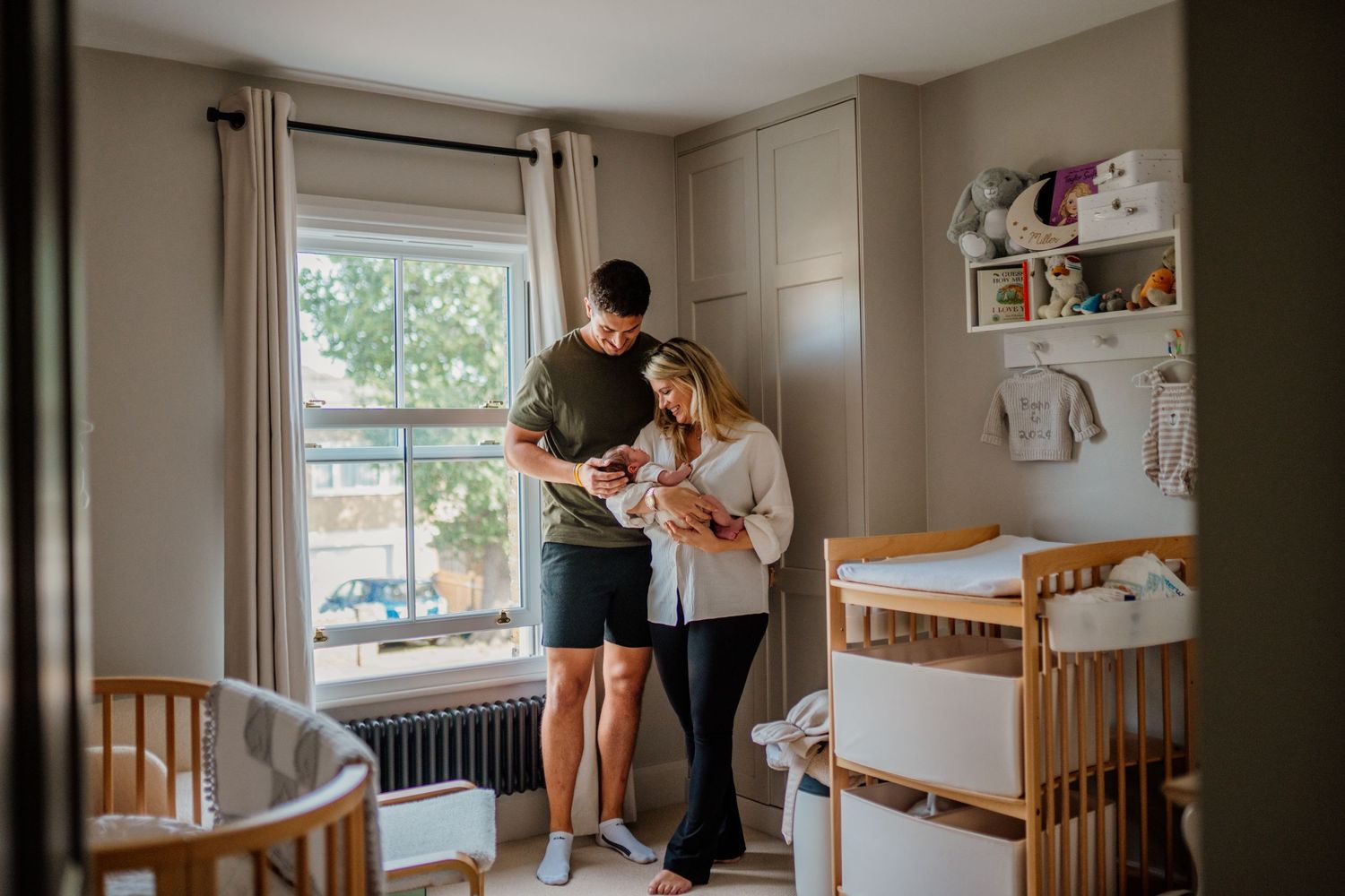 Natural light fills a nursery room with wooden crib and changing table.