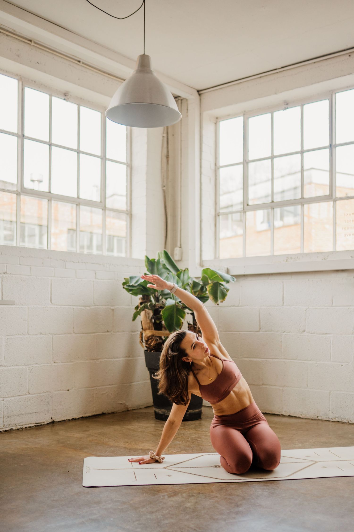 Series of yoga poses demonstrated on a white mat in a bright, minimalist studio space.