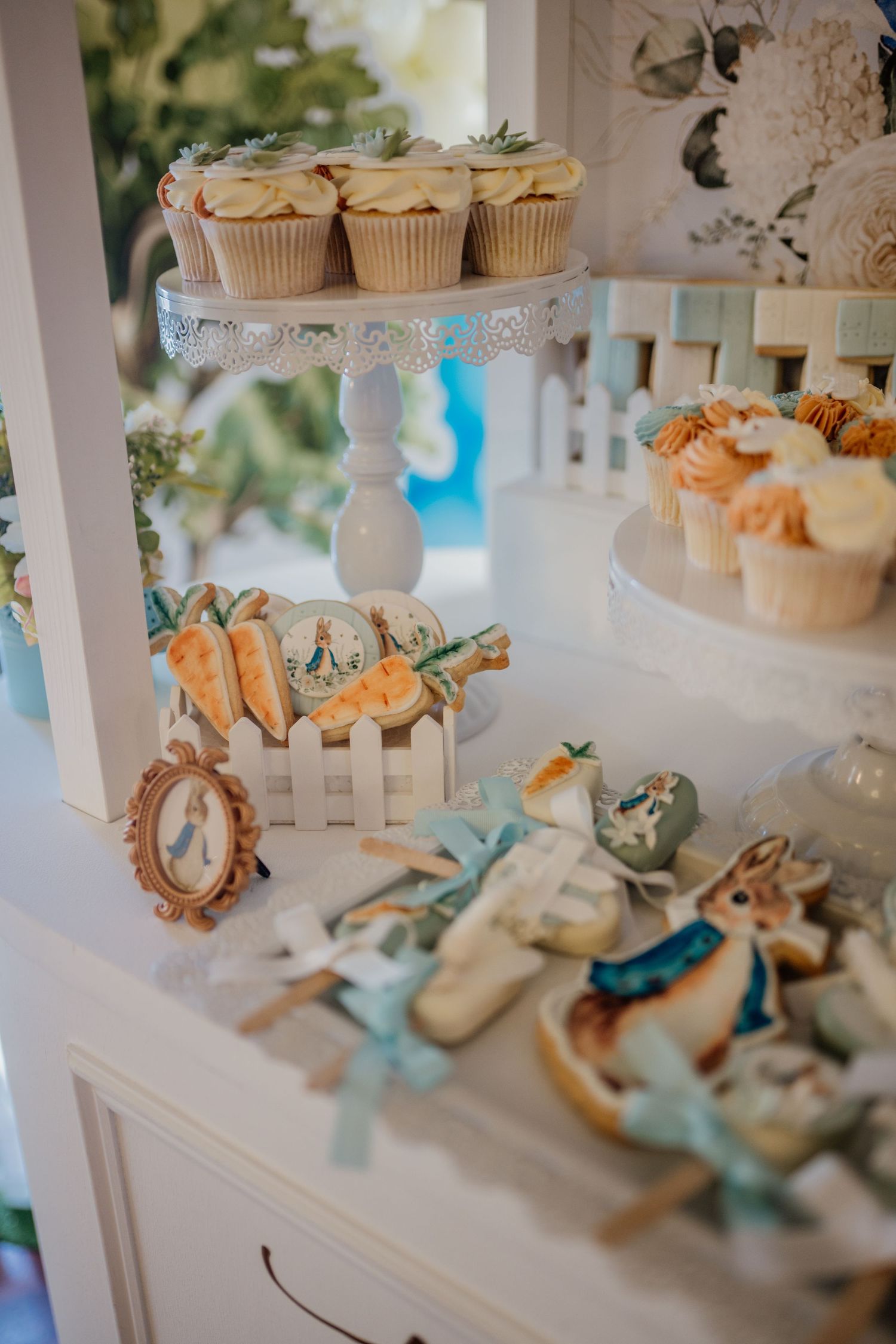 Elegant dessert display with cupcakes and decorative items in white and blue theme.