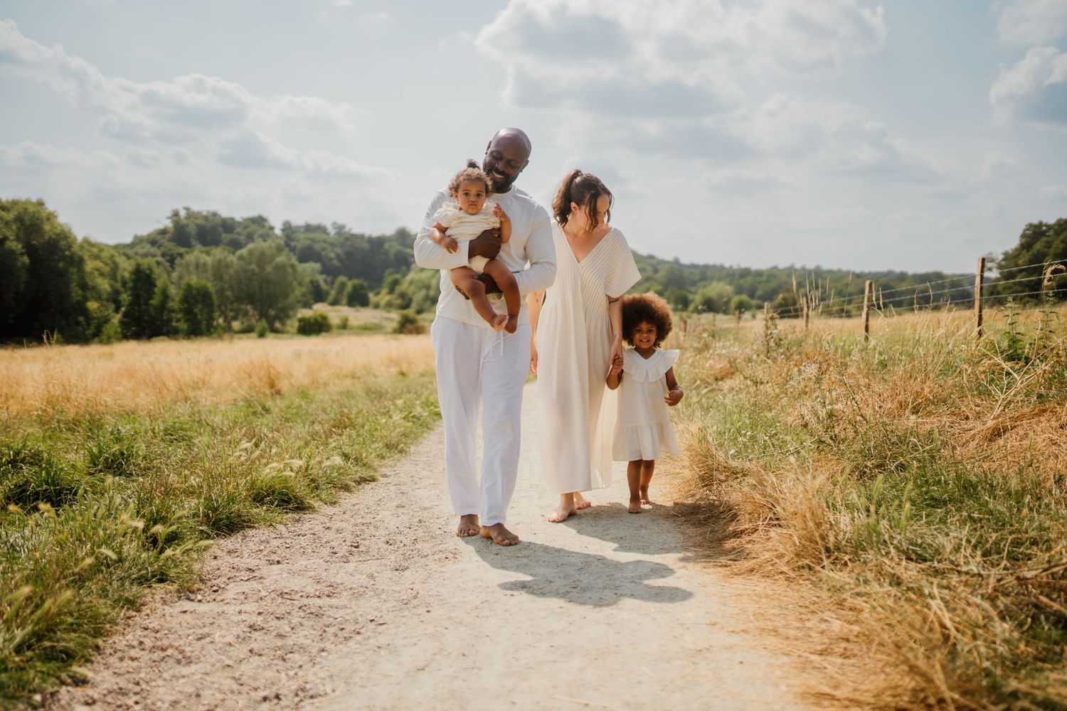 Family enjoying outdoor walk together on dirt path through countryside.