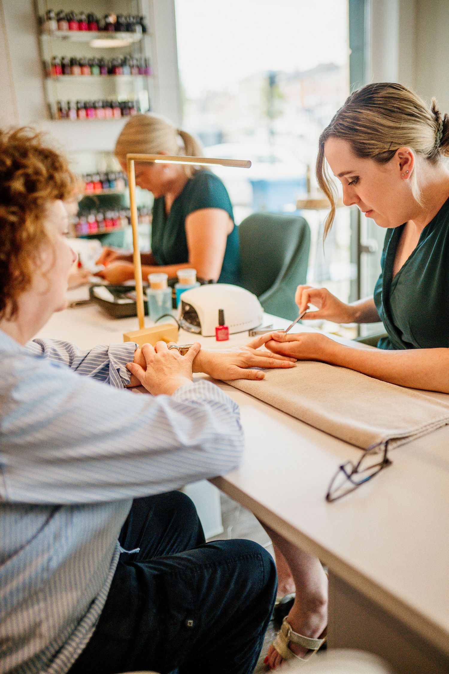 People seated at a white counter focusing on nail care services.
