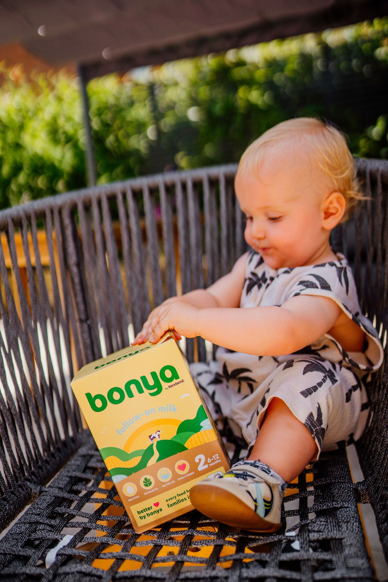 Child playing with colorful food boxes on an outdoor grill.