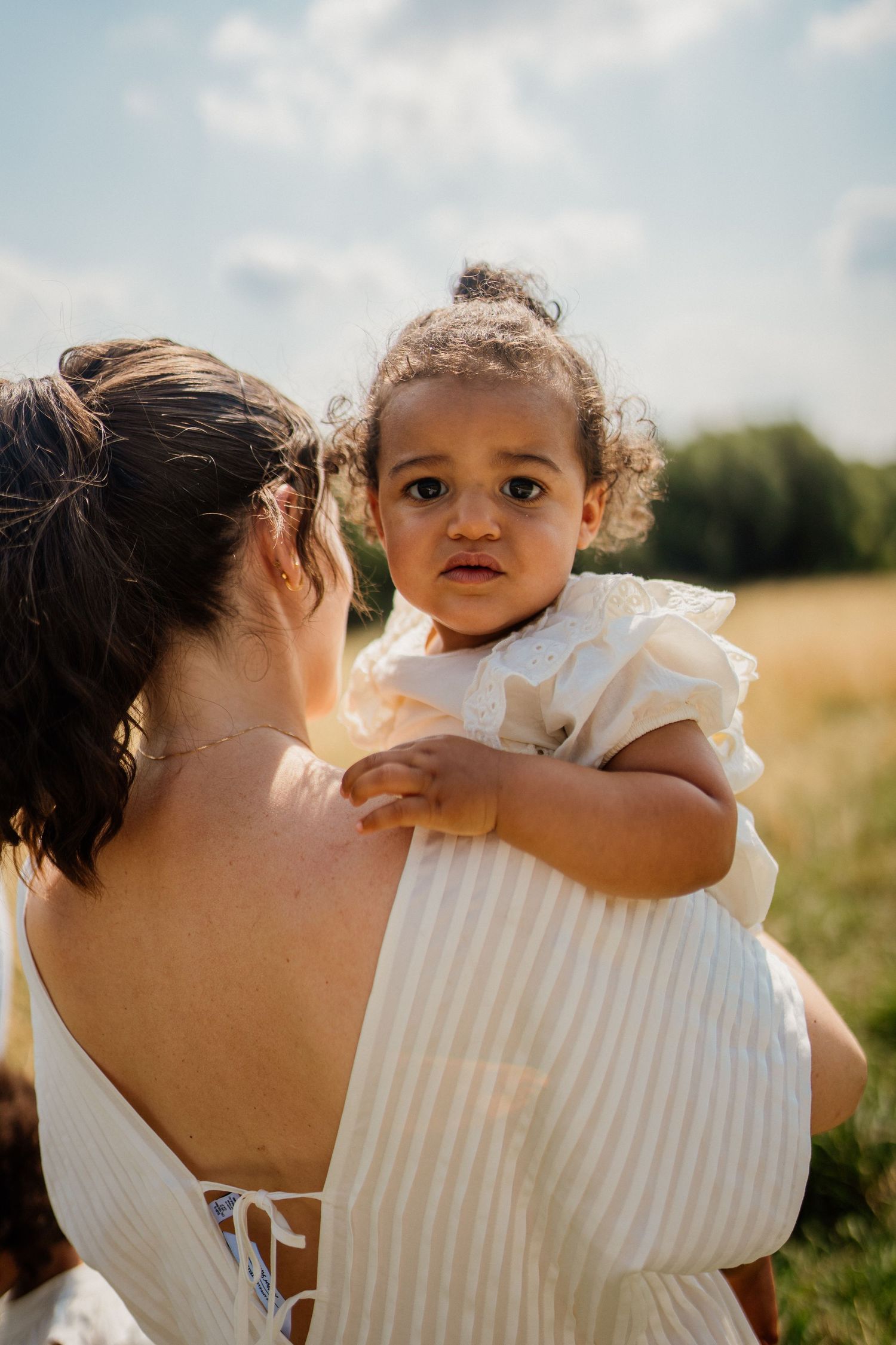 An intimate family moment captured in a sun-drenched summer field.