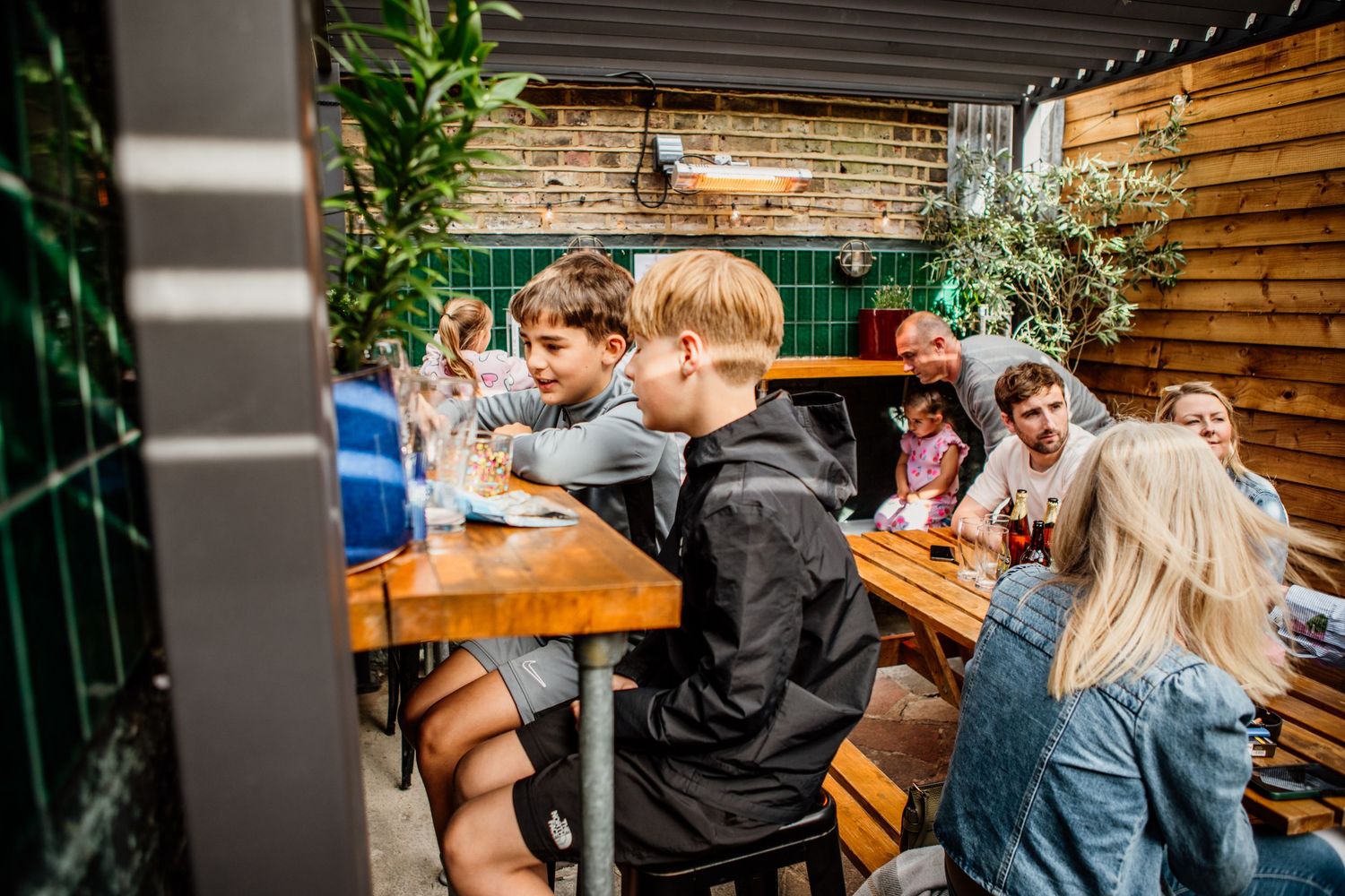 People enjoying drinks and socializing at a casual outdoor beer garden patio on a sunny day.