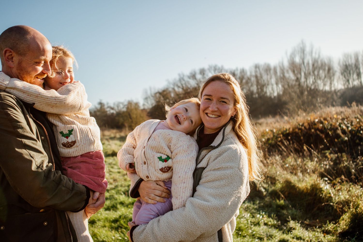Happy family enjoying a warm sunset moment together in a grassy field.