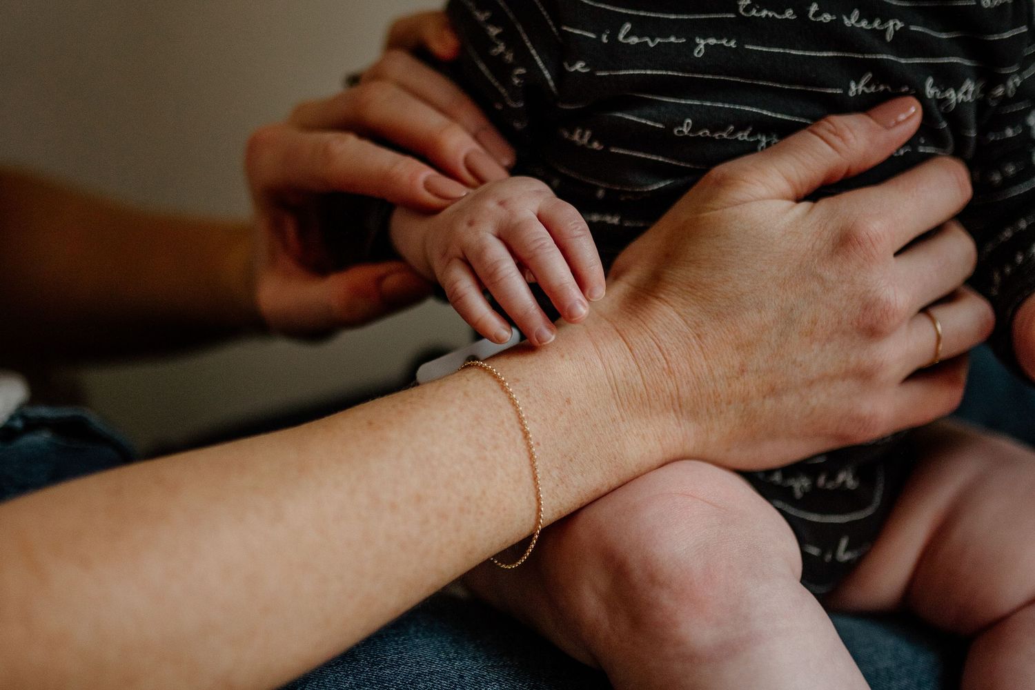 Close-up of hands resting on a dark surface with delicate jewelry details.