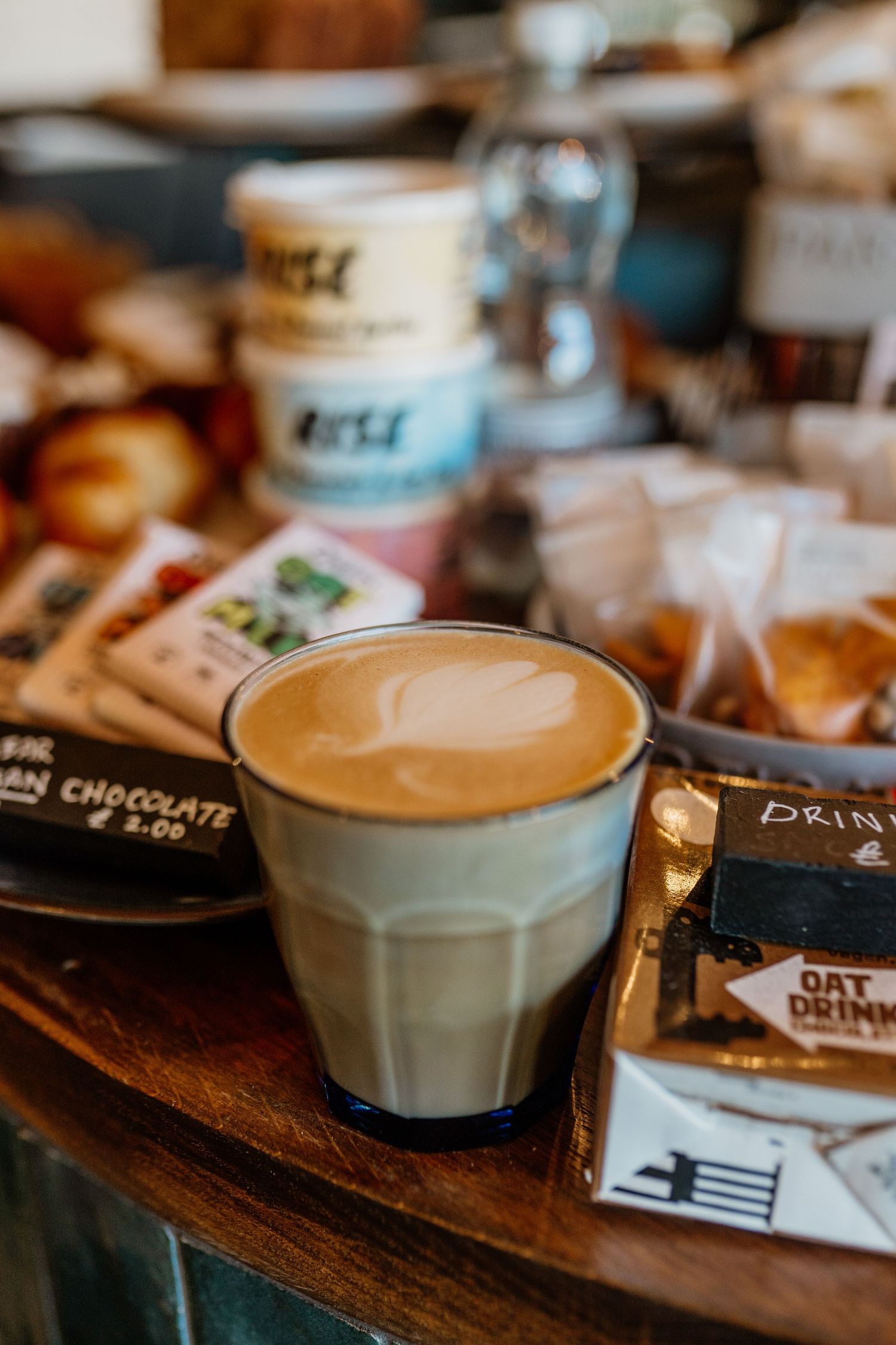 Latte art hearts in white ceramic cups on wooden table with chocolate drink packets.