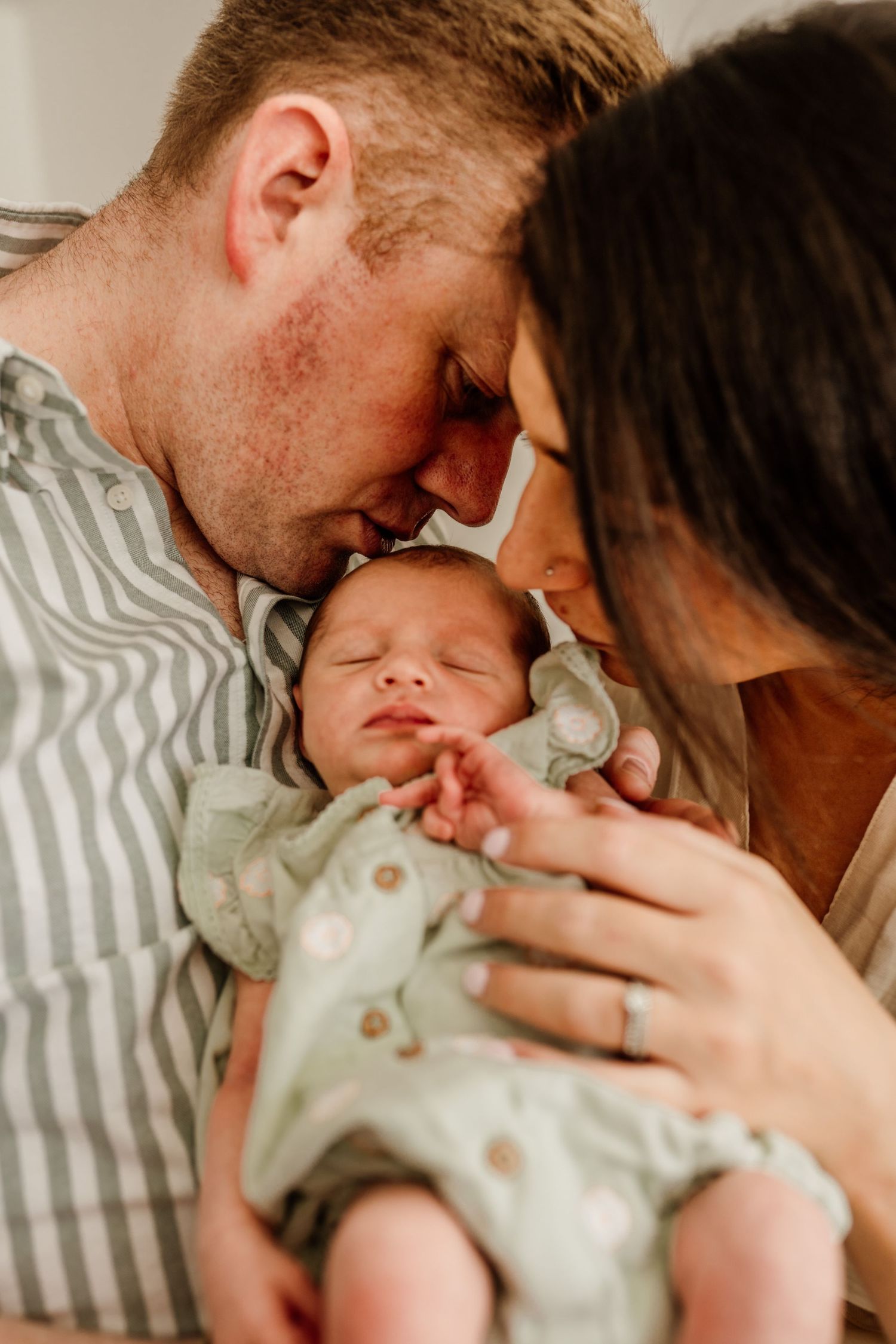 Tender moments with newborn baby in mint green outfit during lifestyle session.