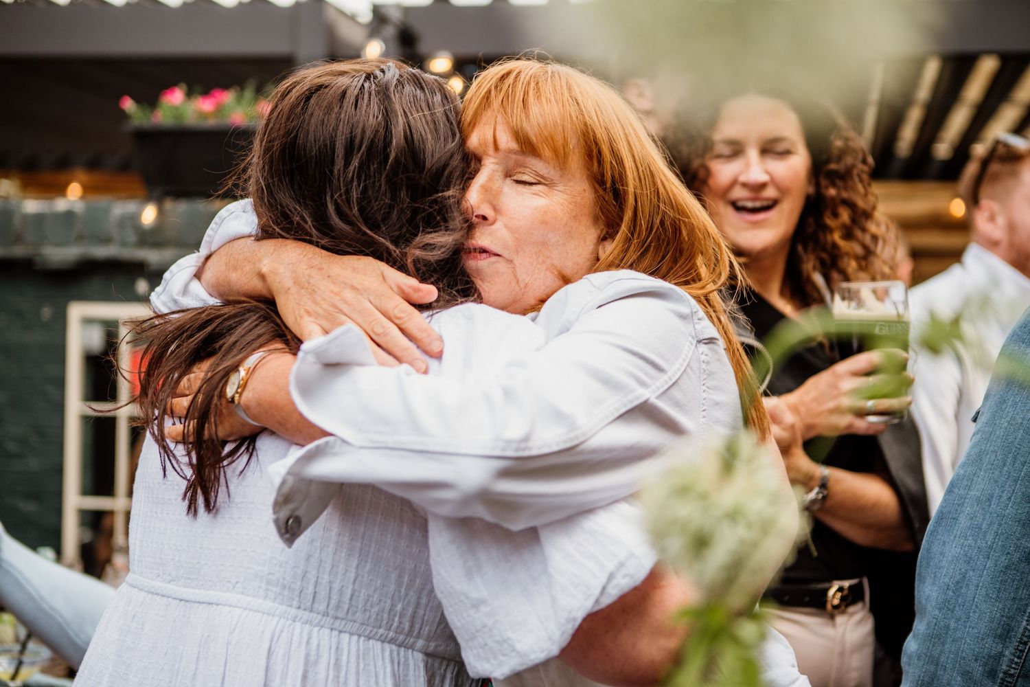 A group of people wearing white outfits embrace in a joyful celebration outdoors.