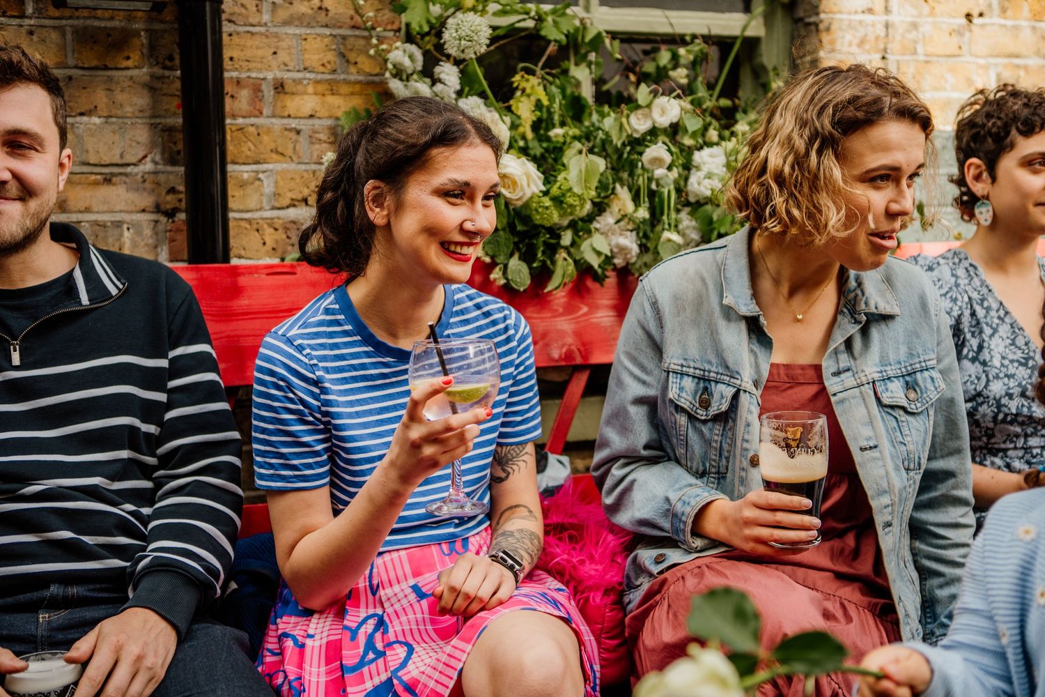 A group of friends enjoying drinks and conversation at an outdoor patio gathering.