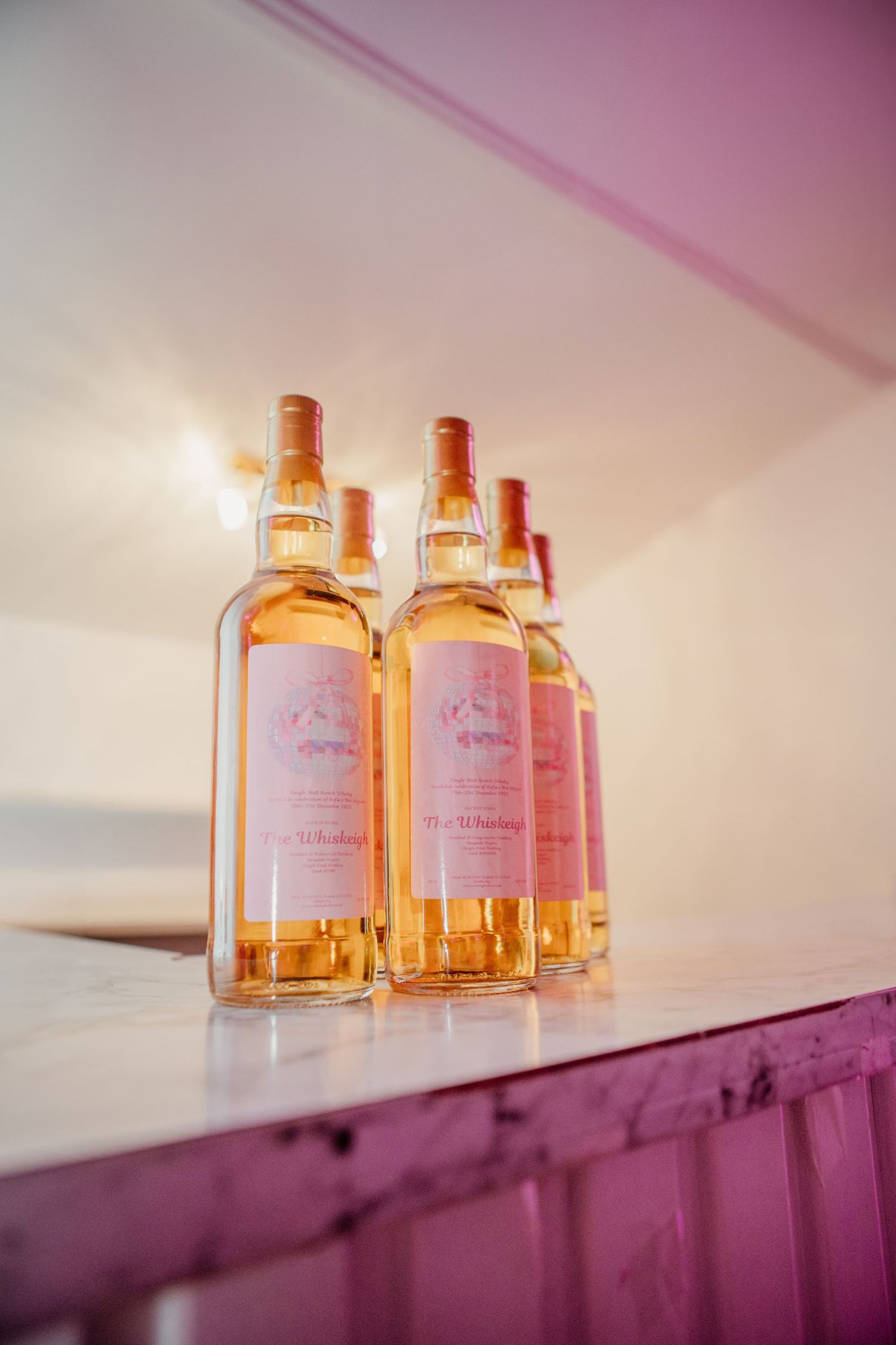 Several amber-colored glass bottles displayed on shelf with pink lighting.