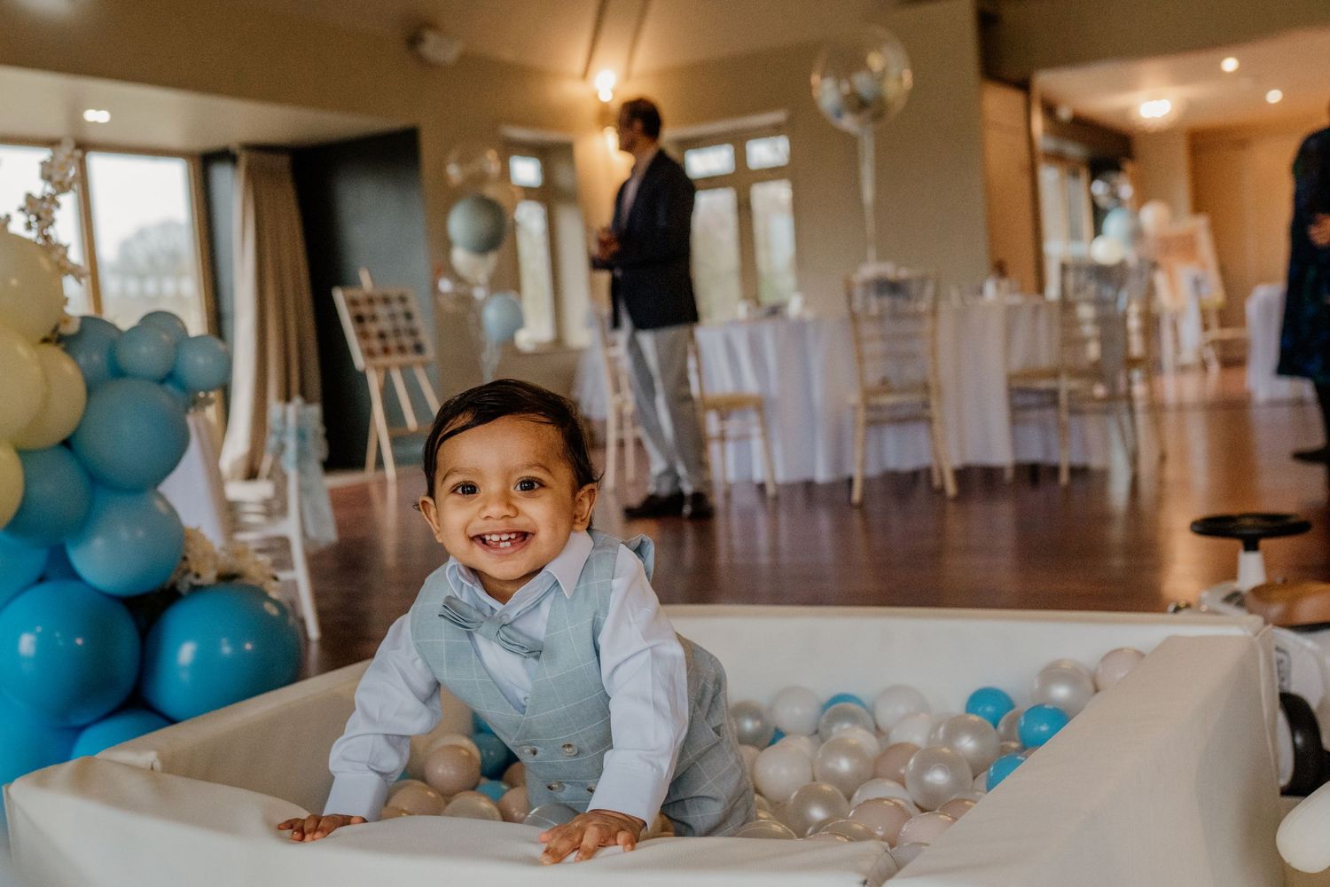 Event space decorated with blue balloons and white chairs for a celebration.